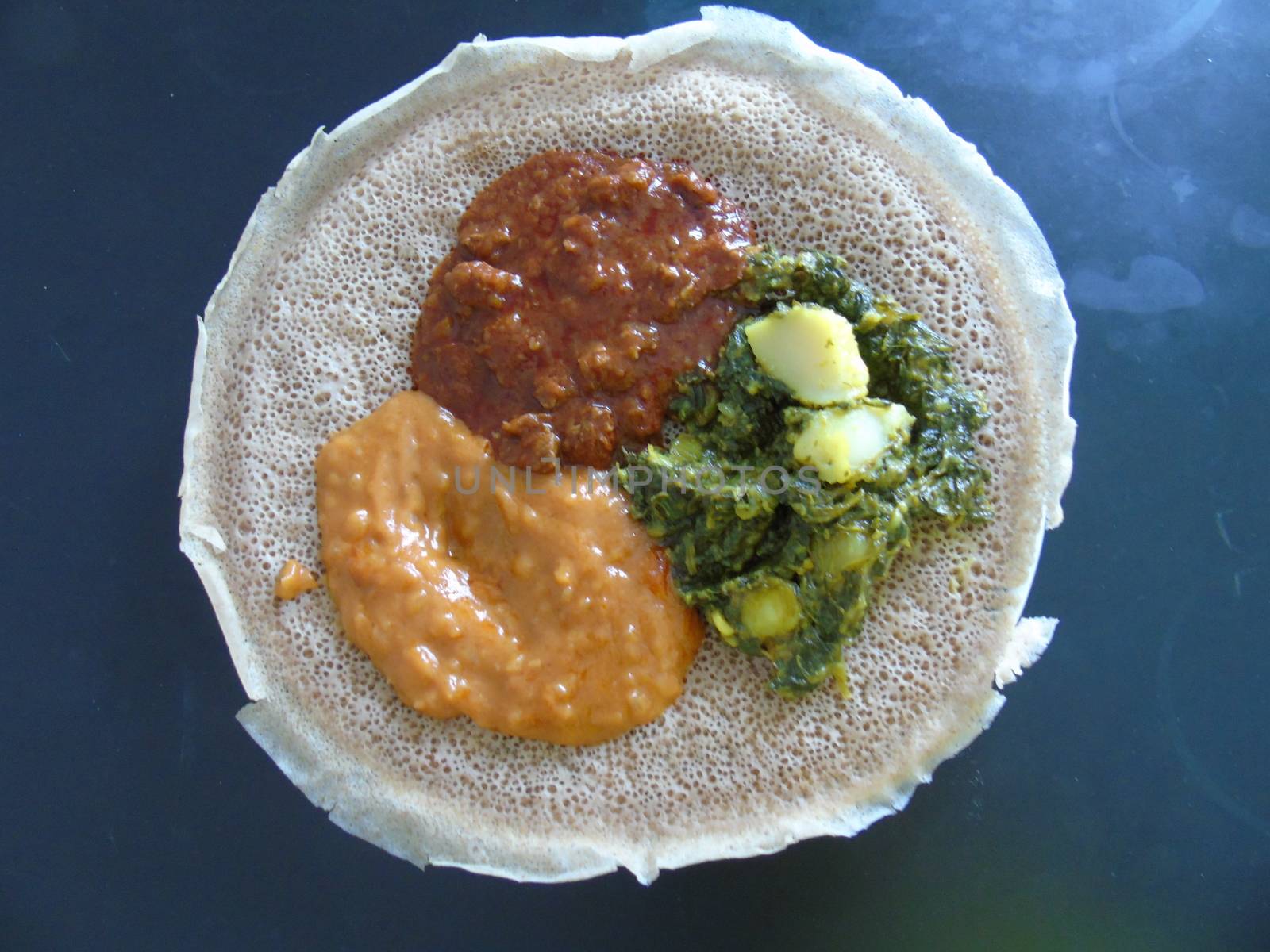 Asmara, Eritrea - 08/05/2020: Ethiopian and Eritrean food, assortment of main dishes. Injera is a sourdough flatbread made from teff flour. It is the national dish of Ethiopia, Eritrea.