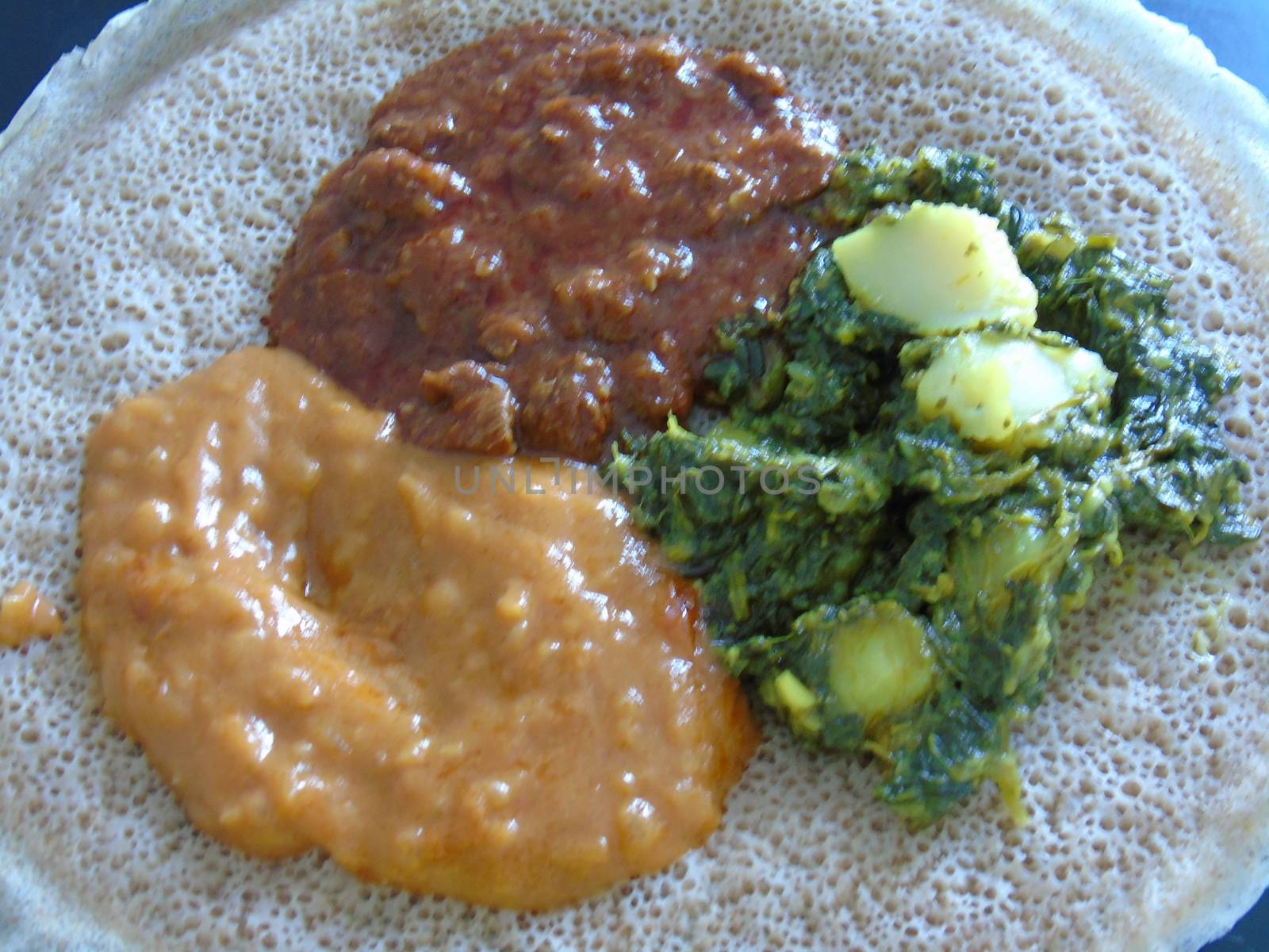 Asmara, Eritrea - 08/05/2020: Ethiopian and Eritrean food, assortment of main dishes. Injera is a sourdough flatbread made from teff flour. It is the national dish of Ethiopia, Eritrea.