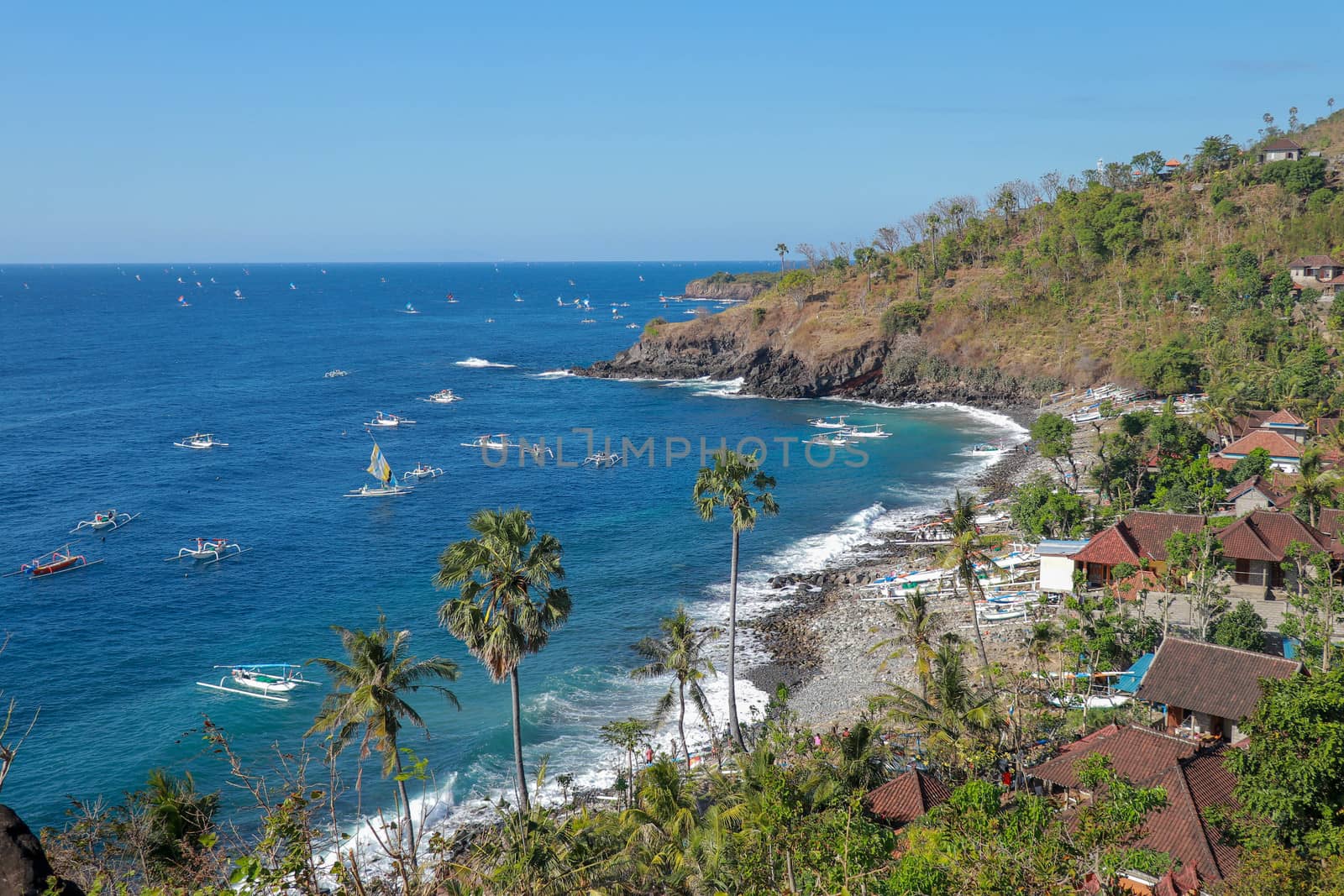 BALI, INDONESIA - JULY 29, 2019: A fisherman in traditional sailing jukung outrigger canoe returning with his catch to Amed, Japanese Wreck beach in Bali, Indonesia.
