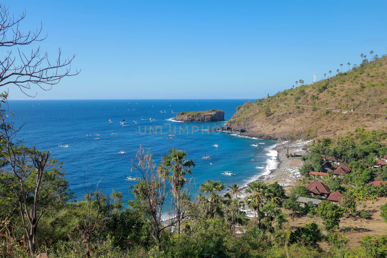 BALI, INDONESIA - JULY 29, 2019: A fisherman in traditional sailing jukung outrigger canoe returning with his catch to Amed, Japanese Wreck beach in Bali, Indonesia.