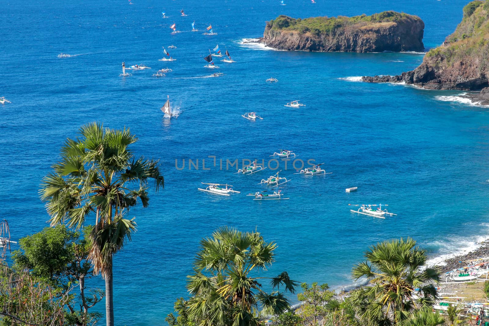 BALI, INDONESIA - JULY 29, 2019: A fisherman in traditional sailing jukung outrigger canoe returning with his catch to Amed, Japanese Wreck beach in Bali, Indonesia.