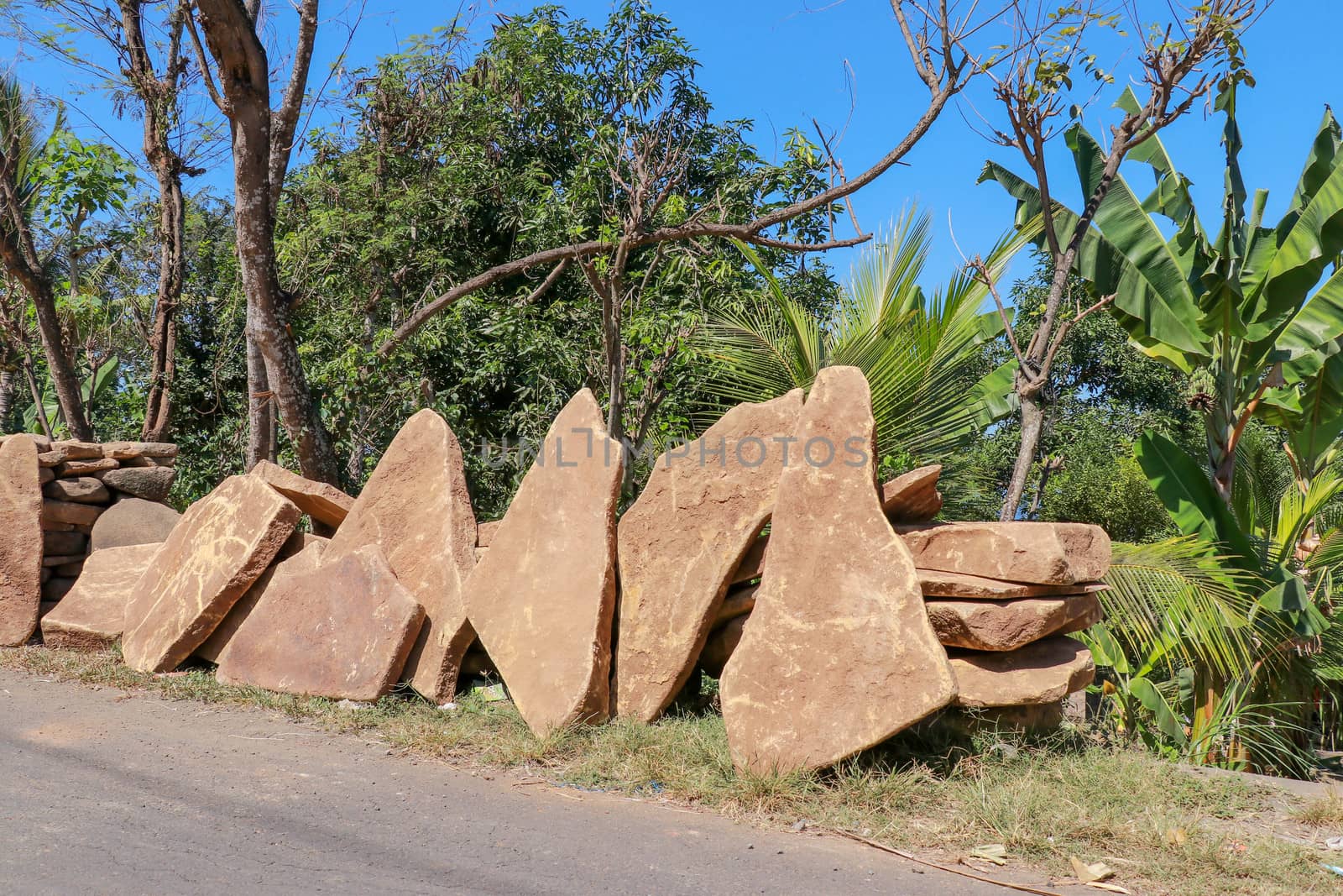 Big flat stones of yellow color for pathway. Natural building material. Boulders stacked on top of each other and ready for sale. Huge heavy stones.