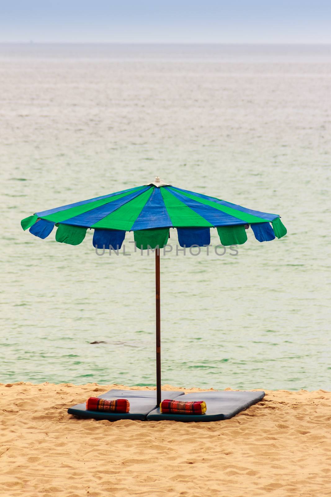 Beautiful sandy beach with umbrella, mattress and pillow by kwhisky