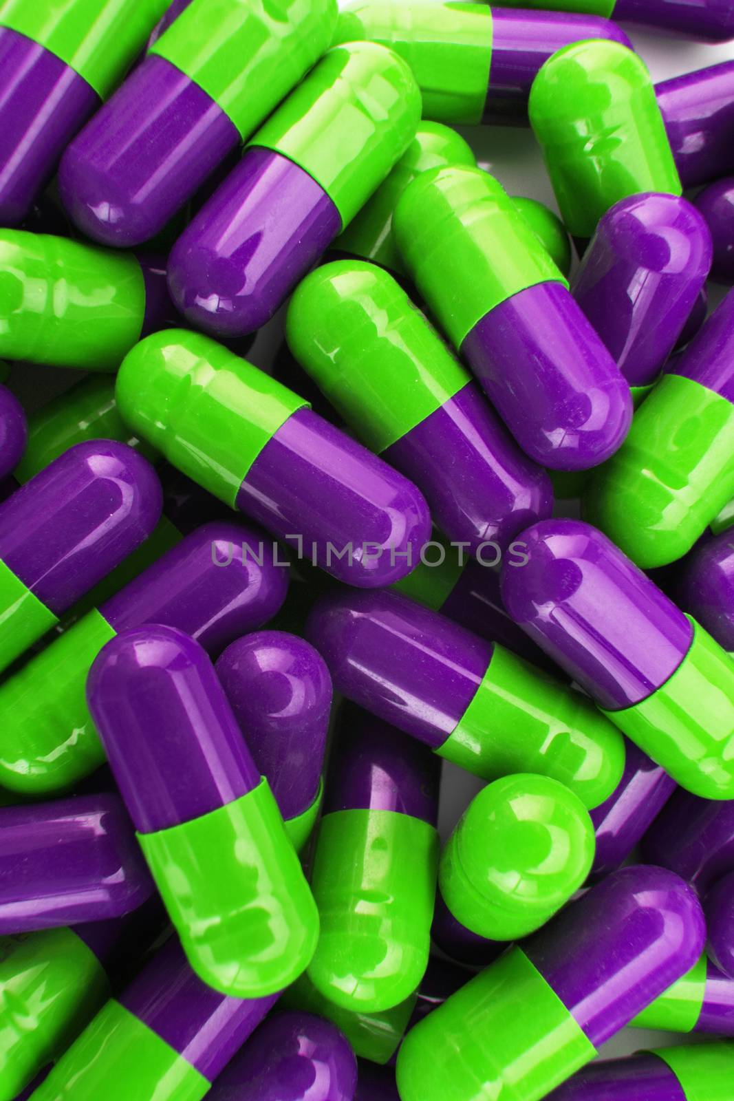 A pile of green and purple capsual pills
