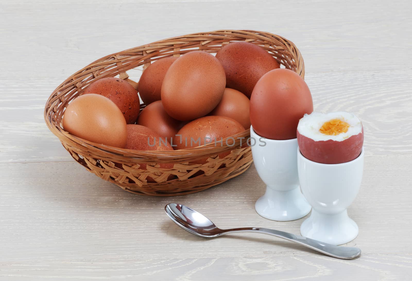 A boiled egg with basket of eggs eggcups