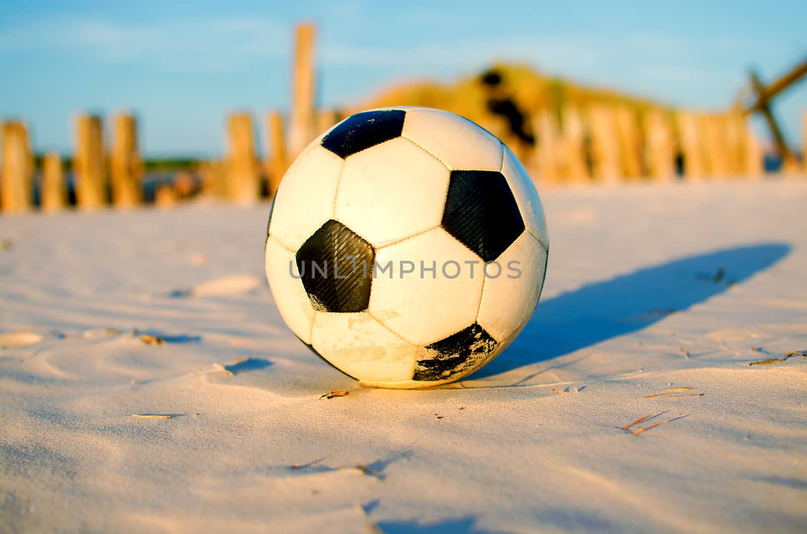 Classic black and white football soccer ball sits on sand beach