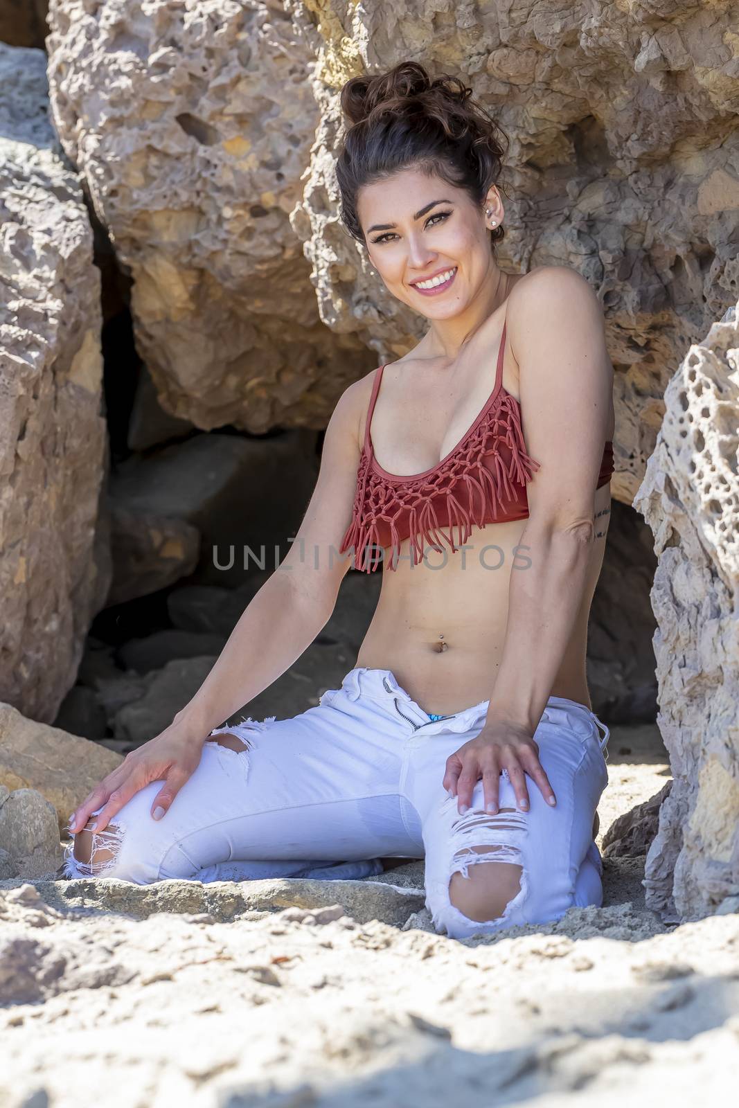 A gorgeous brunette bikini model lounging on the shoreline at the beach on a sunny day