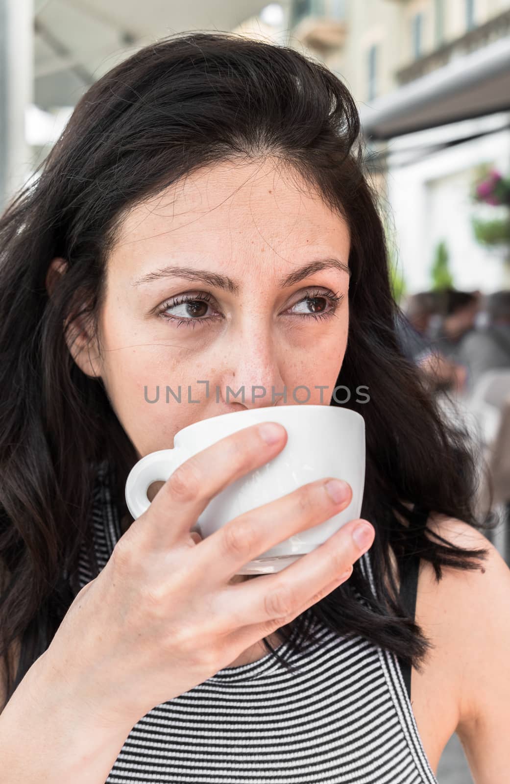 Pensive pretty young woman drinking in an outdoor local a beverage. Lifestyle and concepts.