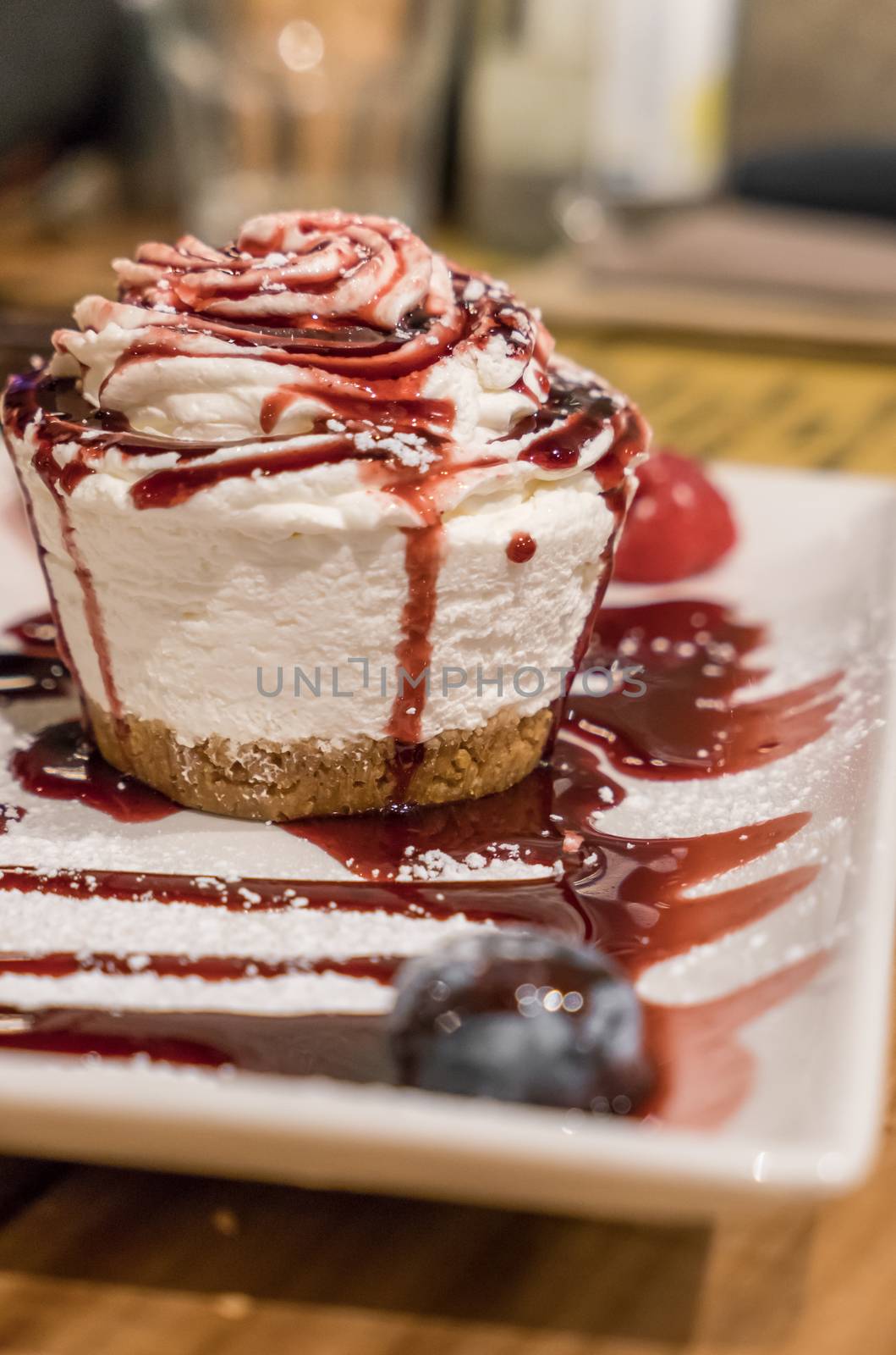 Round small cheesecake with sauce to forest fruit, with a sprinkling of powdered sugar.