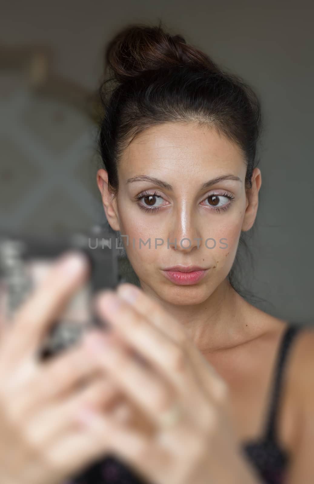 Brunette woman caucasian looking at herself in the mirror. The hands are blurred. Ideal for concepts.