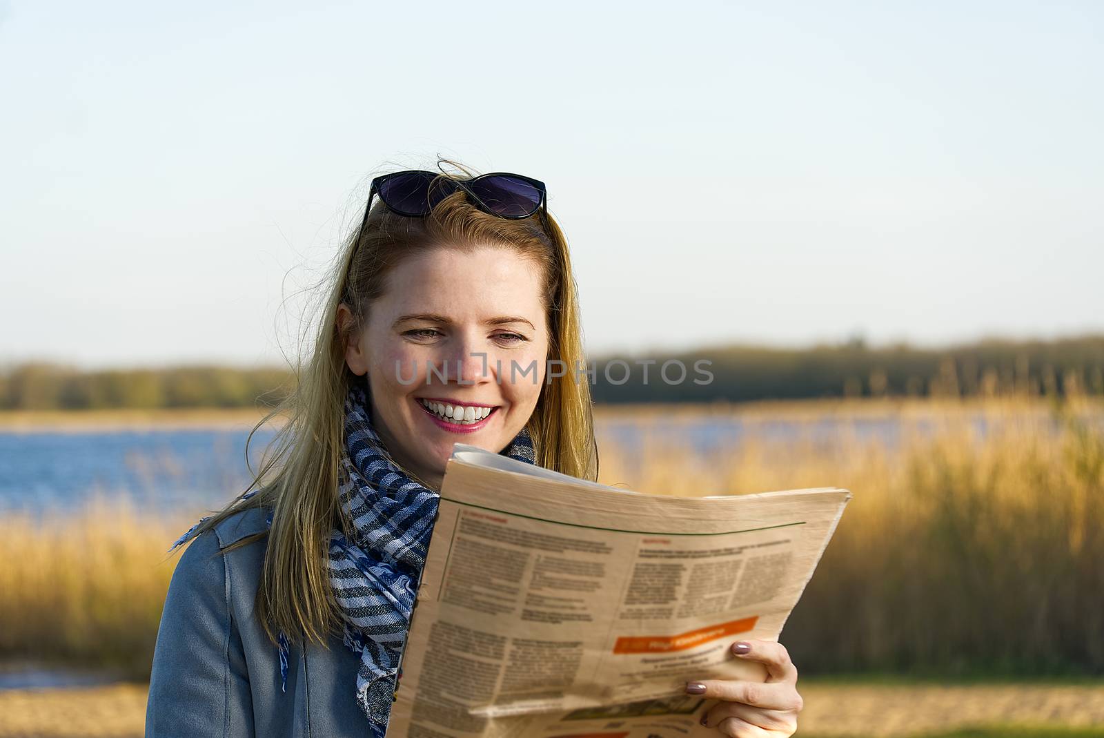 happy woman reading newspaper near lake. fine news concept