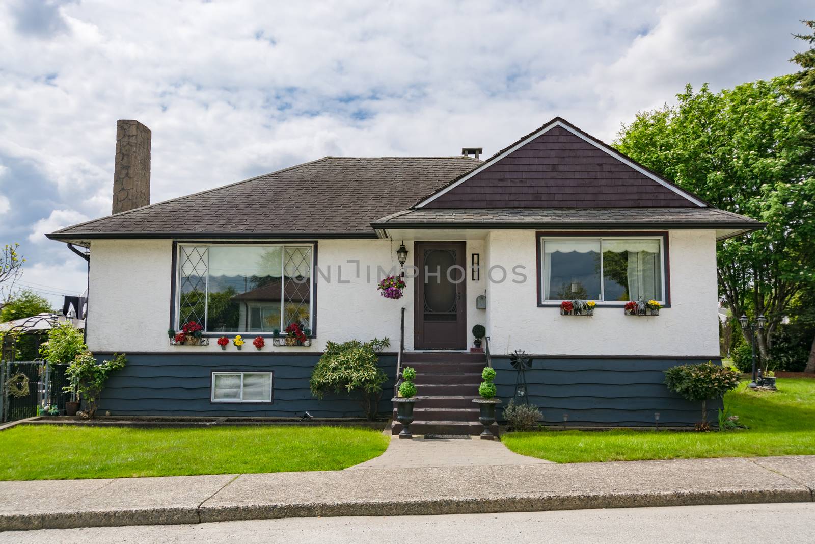 Small family house with green lawn in front. Average residential house on cloudy day in British Columbia