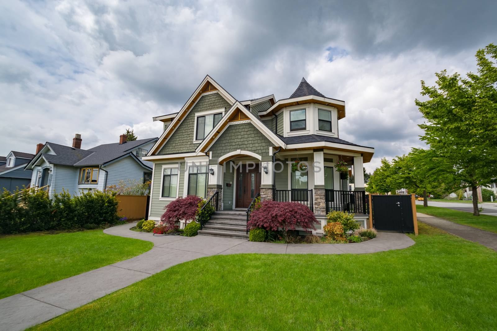 Residential family house with concrete pathway over front yard. Family house on cloudy day in British Columbia, Canada