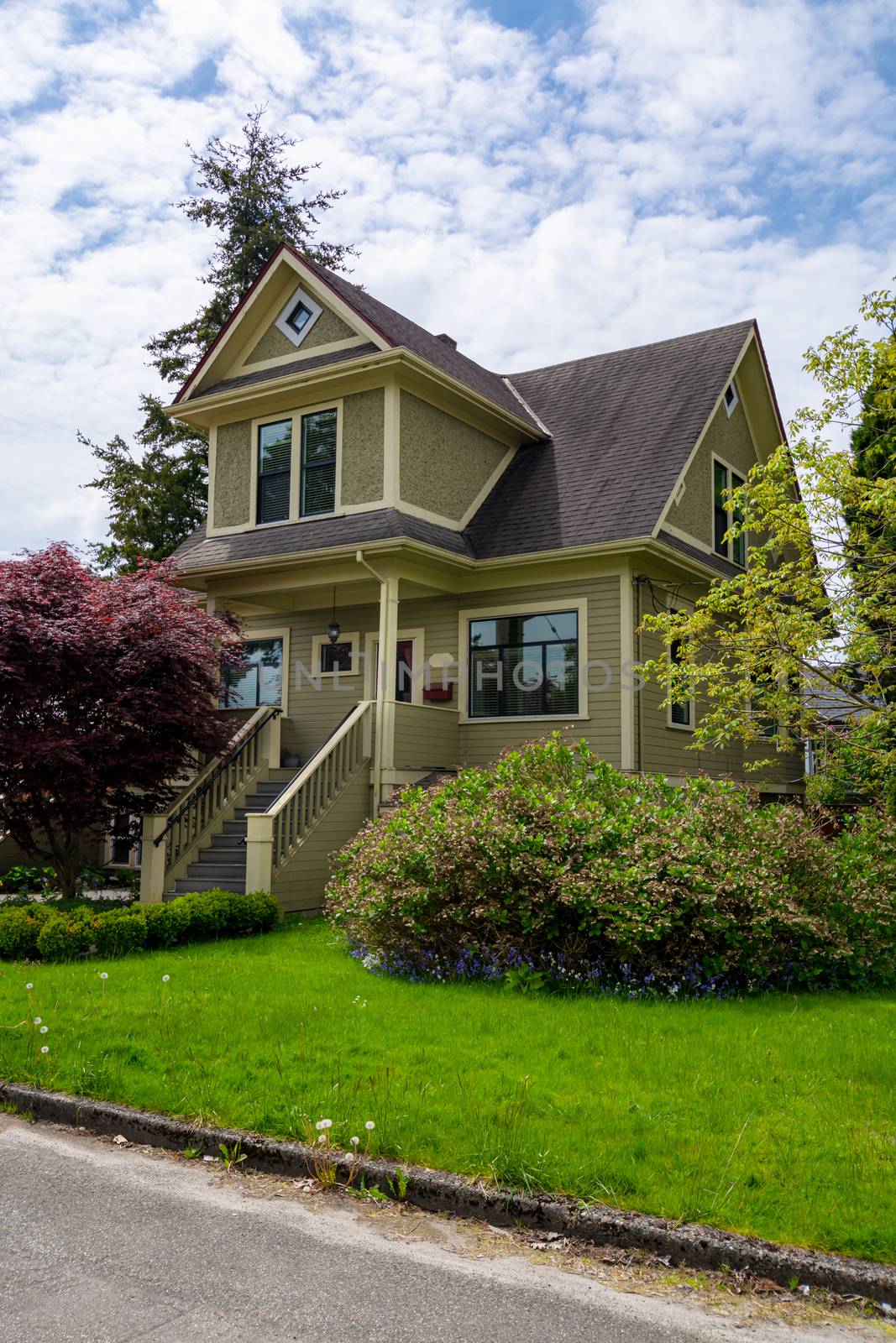 Residential family house with stairwell to main entrance and green lawn in front. Family house with entrance door under the porch