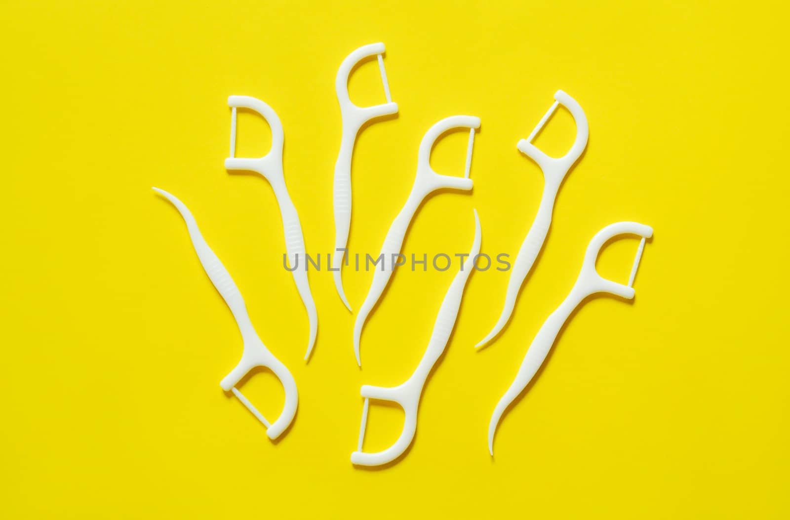 Dental floss, white color toothpick. Isolated on yellow background.