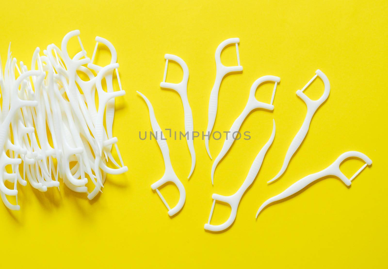 Dental floss, toothpick, oral cleaning device. Isolated on yellow background.