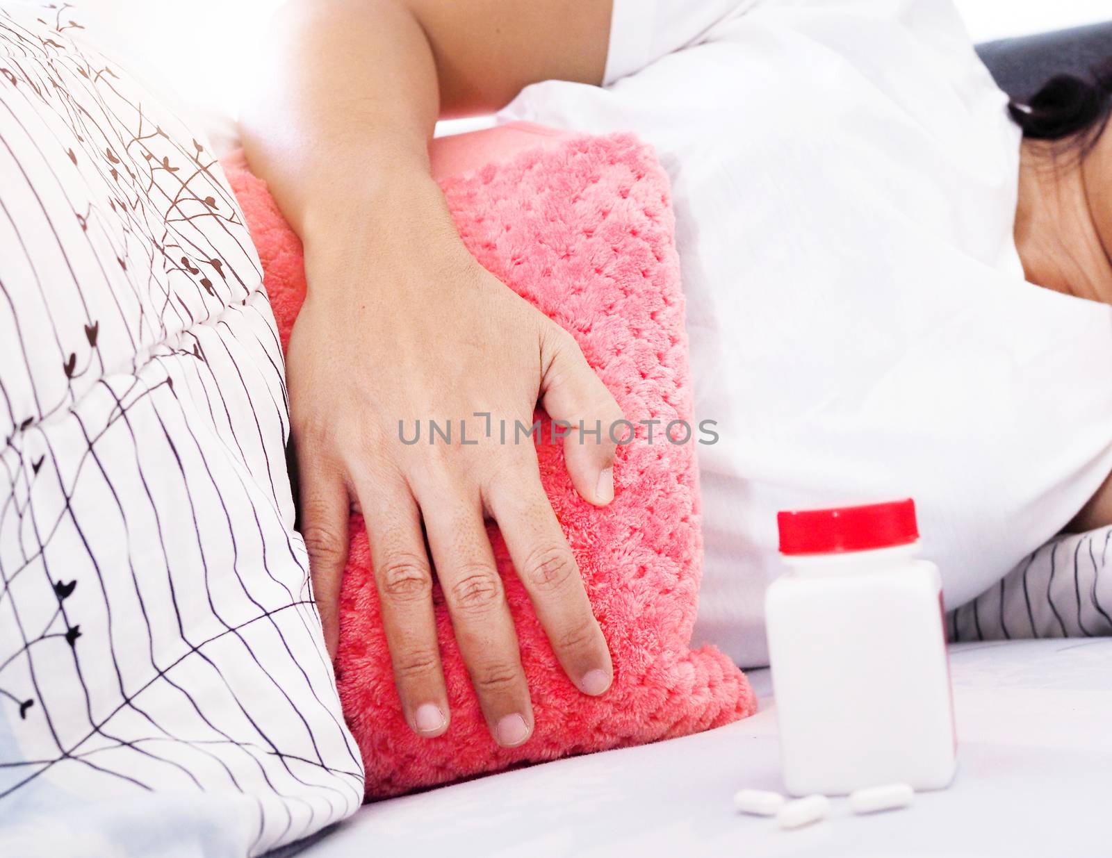Asian women sleep and stomach ache Period cramps. have hot water bags and medicine bottles, painkillers for relief