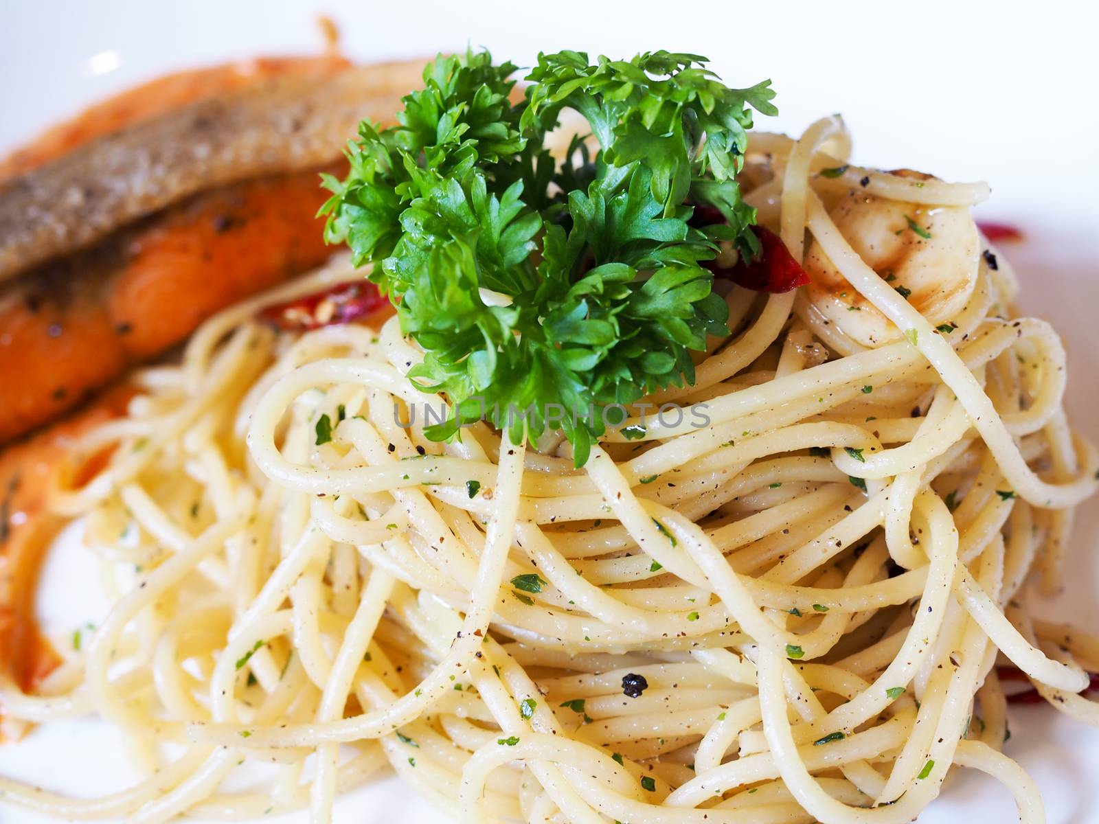 pasta spaghetti with grilled salmon and dill in white plate on food table.