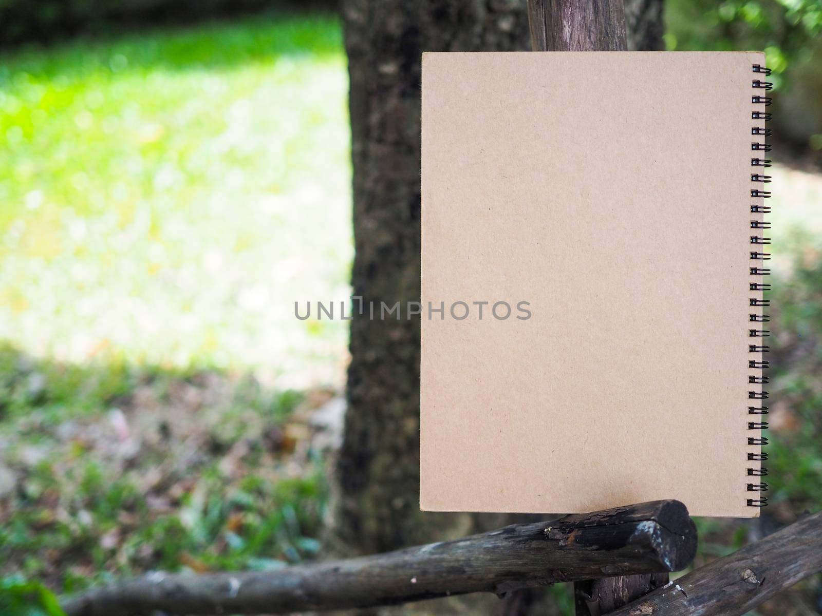 Brown book placed on black wood. Green trees are to look refreshing. Writing work Among the nature in garden. Environmentally friendly concept.