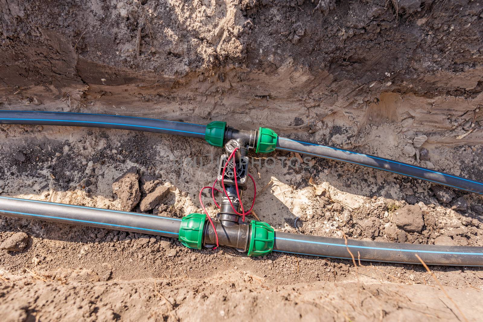 Water pipes (tubes) and control valves for irrigation system placed in a trench in the ground of a park