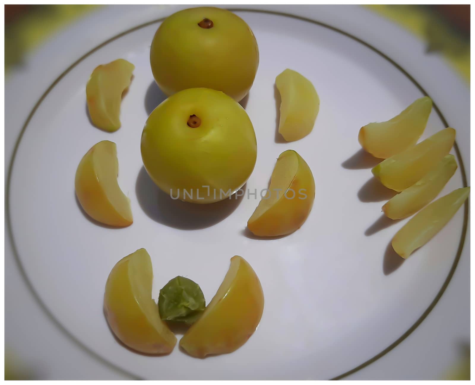 Colorful yellow healthy Gooseberry and its pieces arranged beautifully in white plate and it is rich in fiber control blood sugar good for heart and healthy diet and also rich in Vitamin C