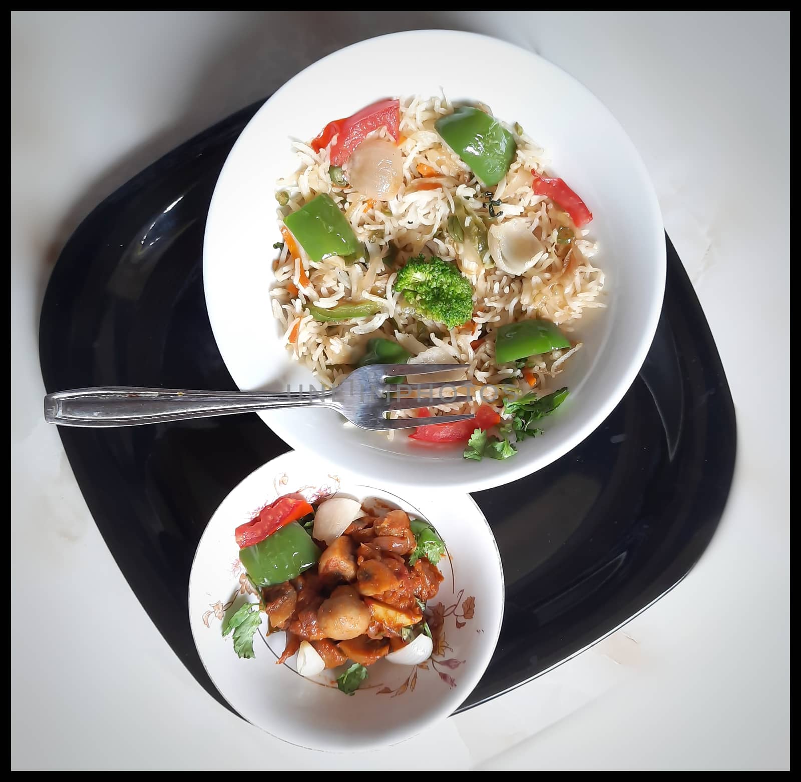 Colorful Delicious Veg fried rice with spicy indian mushroom gravy in white bowl and it's one of favorite restaurant cuisine food