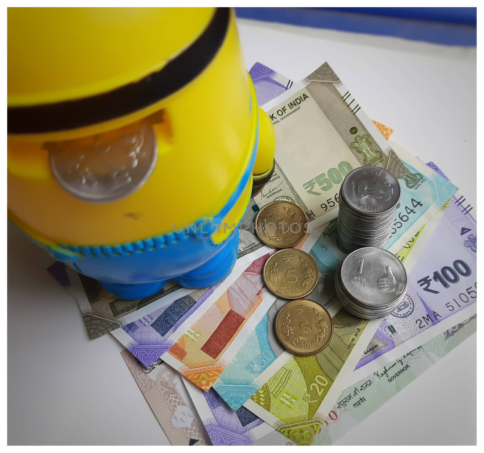 Indian new currency spread randomly with coins in it with yellow color piggy bank with coins in it