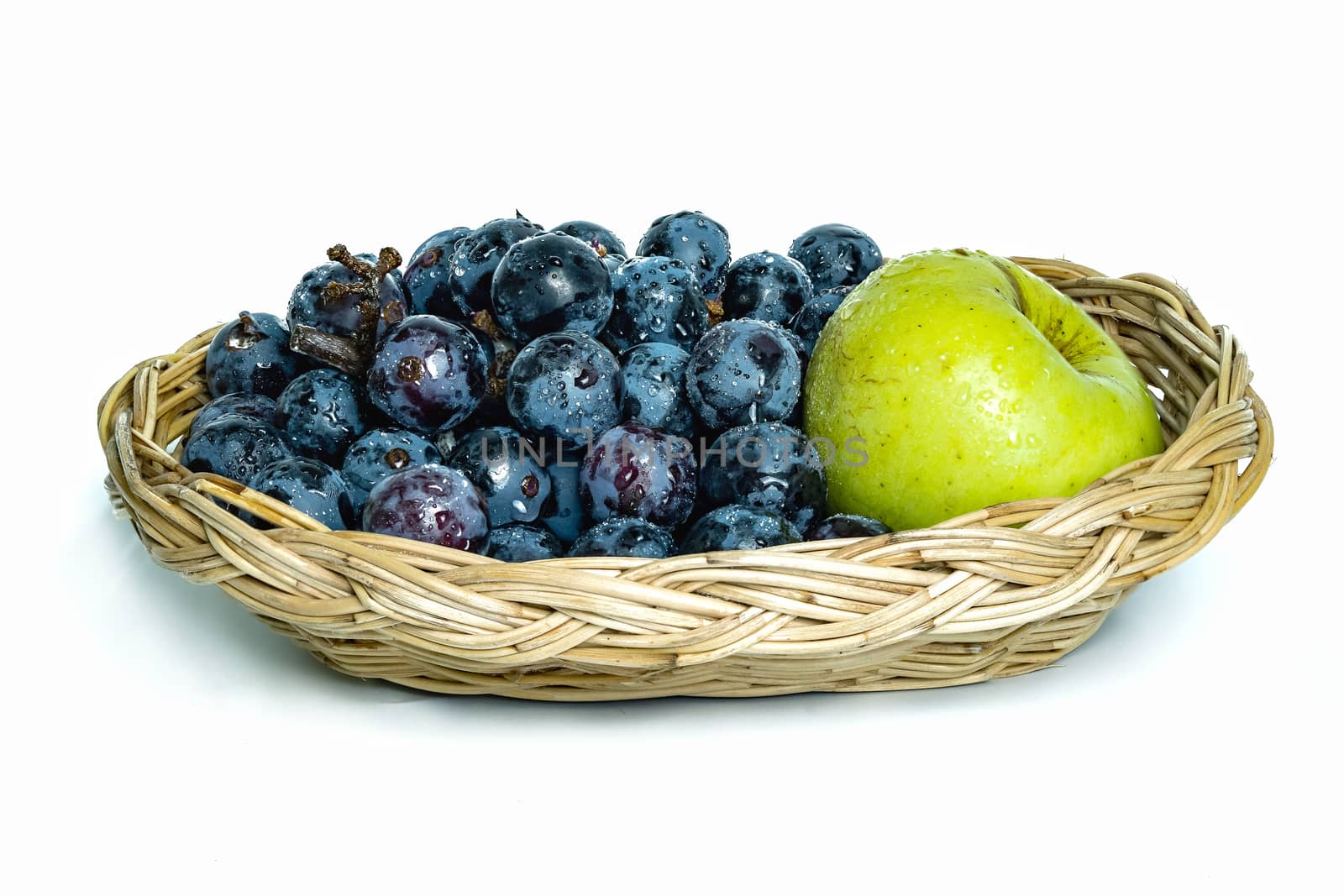 Bright purple grapes and green apples in a wooden basket on a white background.