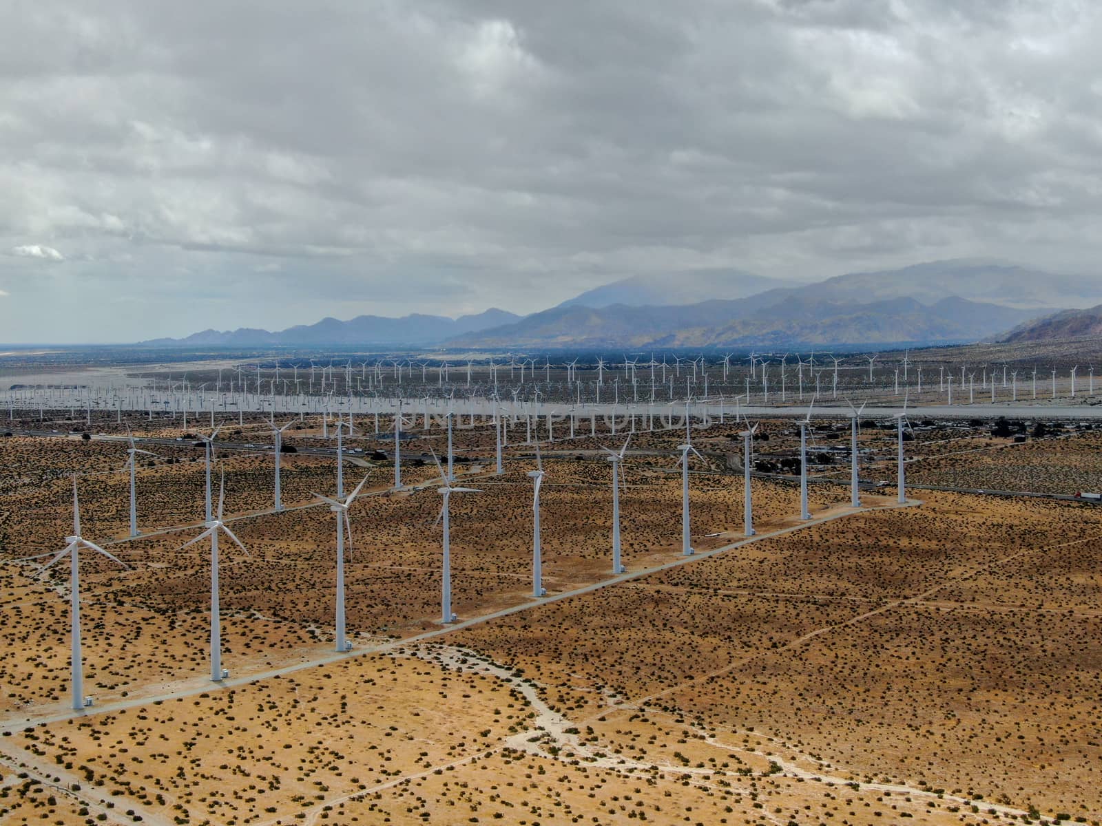 Aerial view of huge array of gigantic wind turbines spreading over the desert in Palm Springs wind farm. California. USA. Aerial view of wind turbines generating electricity. 