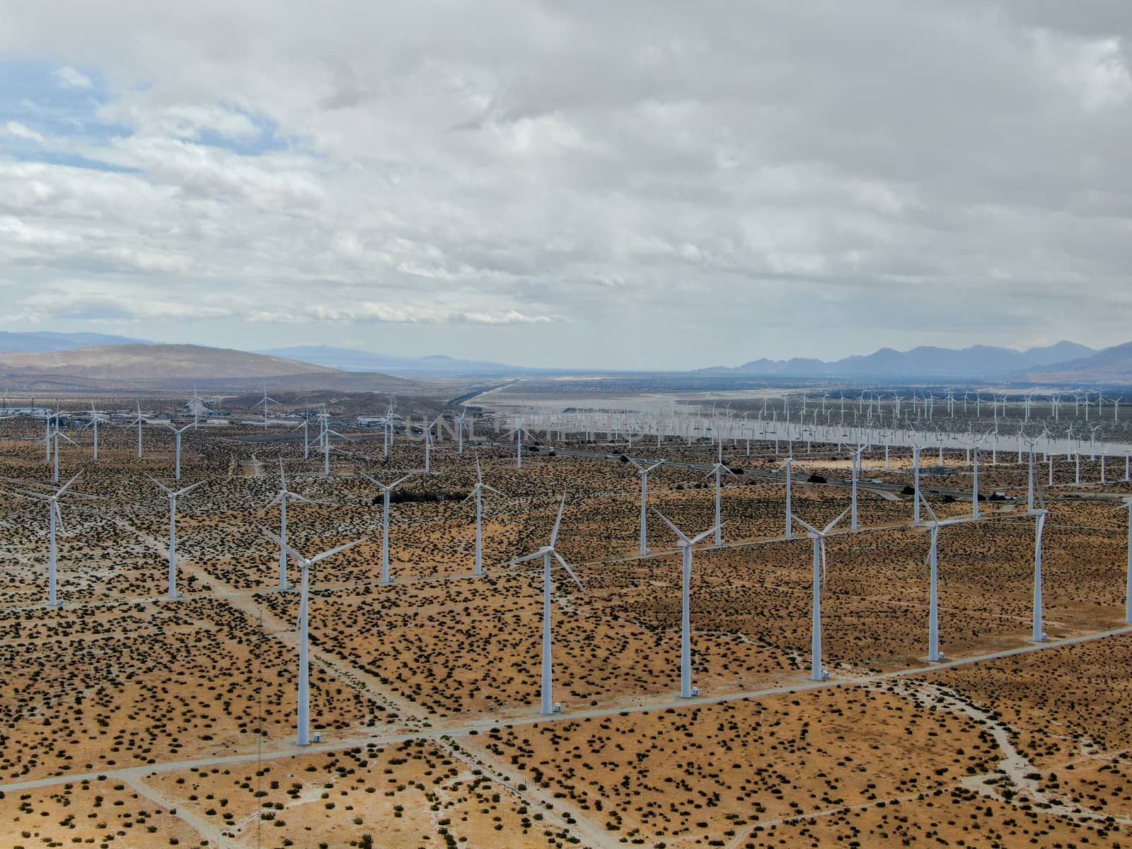 Aerial view of huge array of gigantic wind turbines spreading over the desert in Palm Springs wind farm. California. USA. Aerial view of wind turbines generating electricity. 