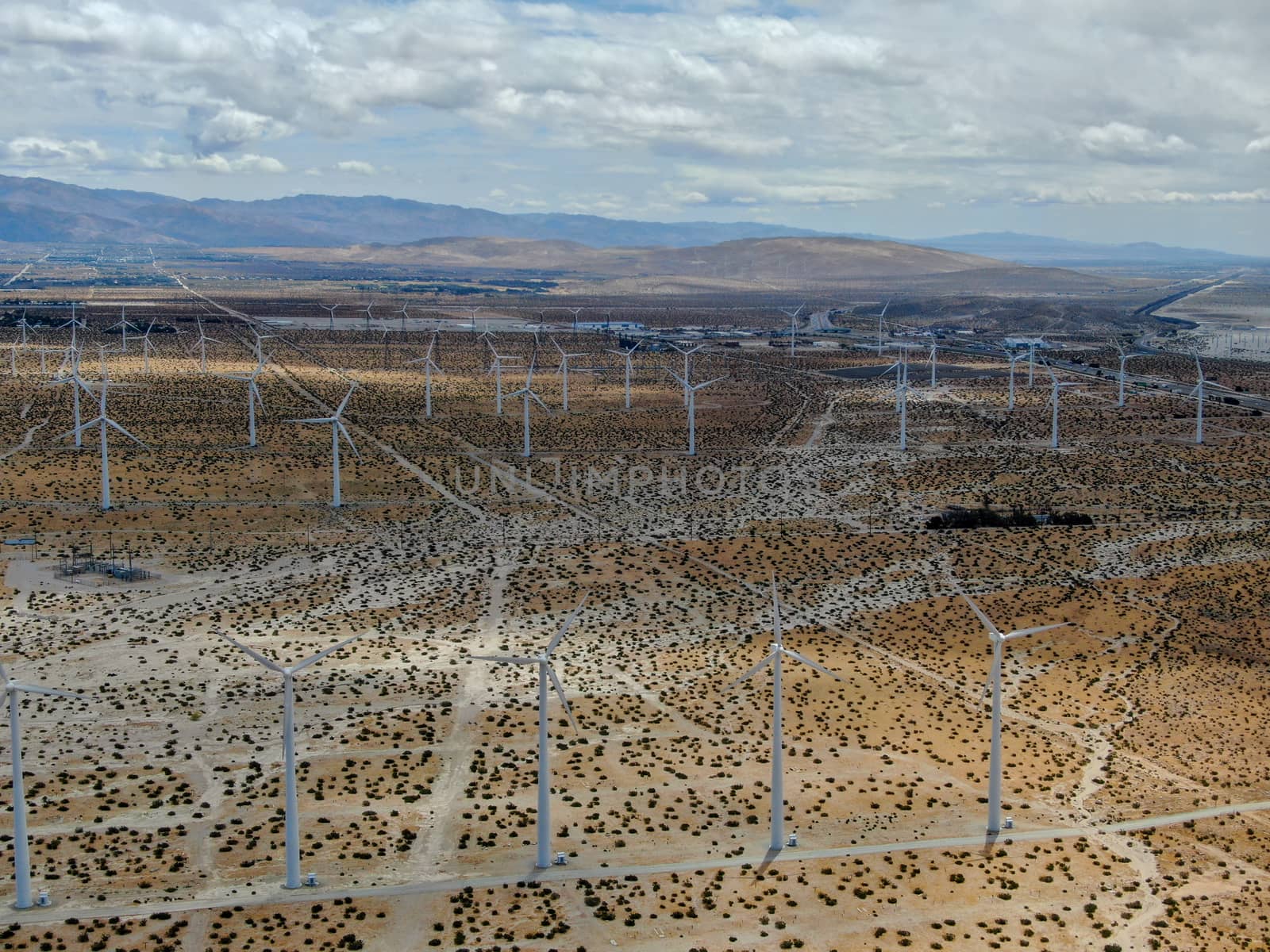 Aerial view of huge array of gigantic wind turbines spreading over the desert in Palm Springs wind farm. California. USA. Aerial view of wind turbines generating electricity. 