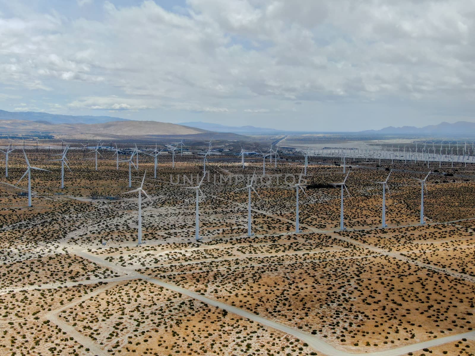 Aerial view of huge array of gigantic wind turbines spreading over the desert in Palm Springs wind farm. California. USA. Aerial view of wind turbines generating electricity. 