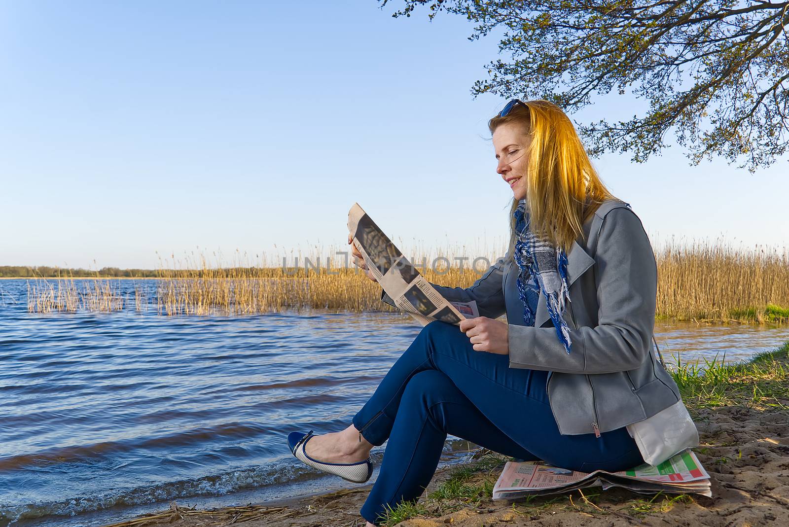 happy woman reading newspaper near lake. fine news concept