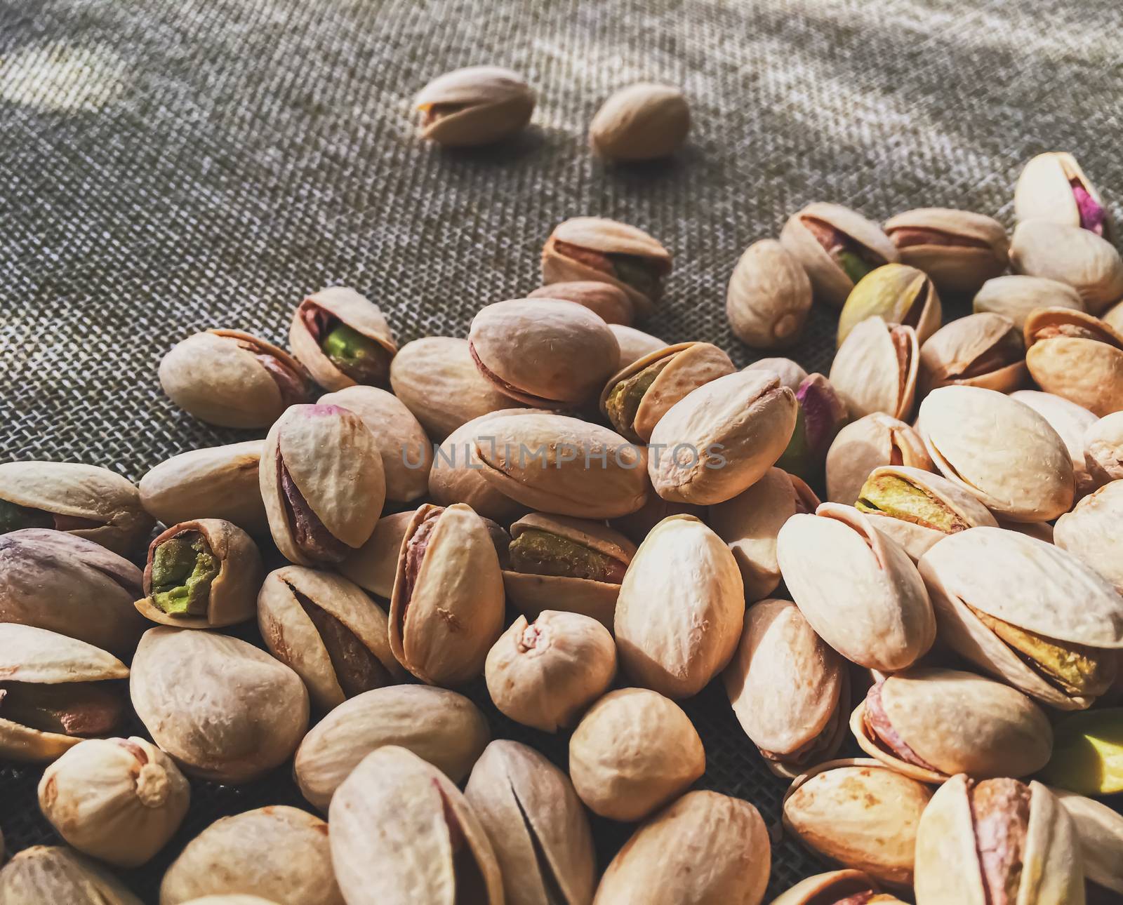 Pistachio nuts on rustic linen background, food and nutrition