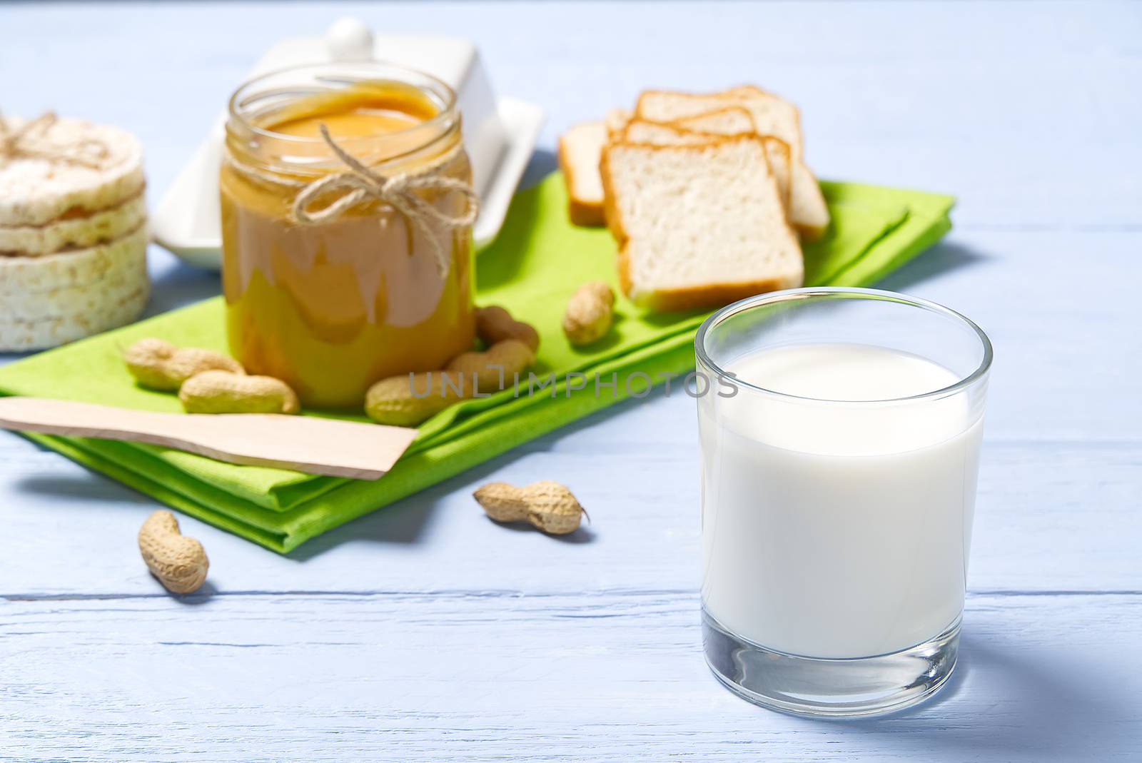 american breakfast milk and peanut butter. Peanut butter, white bread with glass of milk on blue wooden background