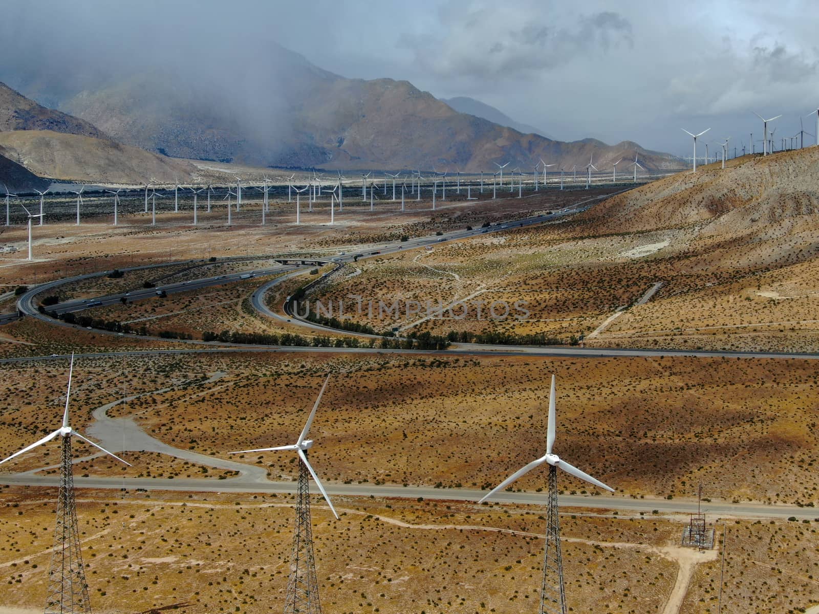 Aerial view of huge array of gigantic wind turbines spreading over the desert in Palm Springs wind farm. California. USA. Aerial view of wind turbines generating electricity. 