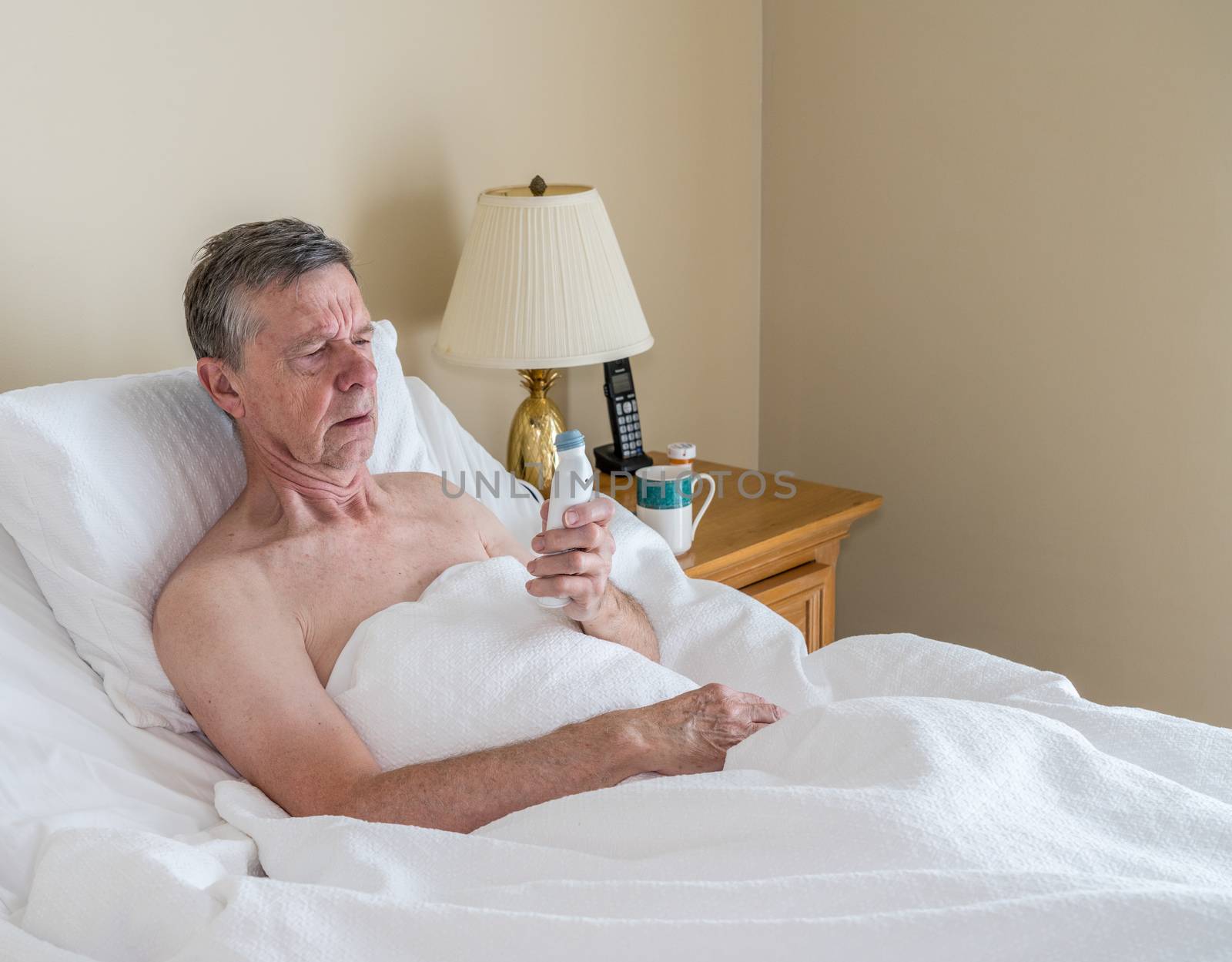 Single caucasian senior man in inclined bed taking temperature with thermometer by steheap