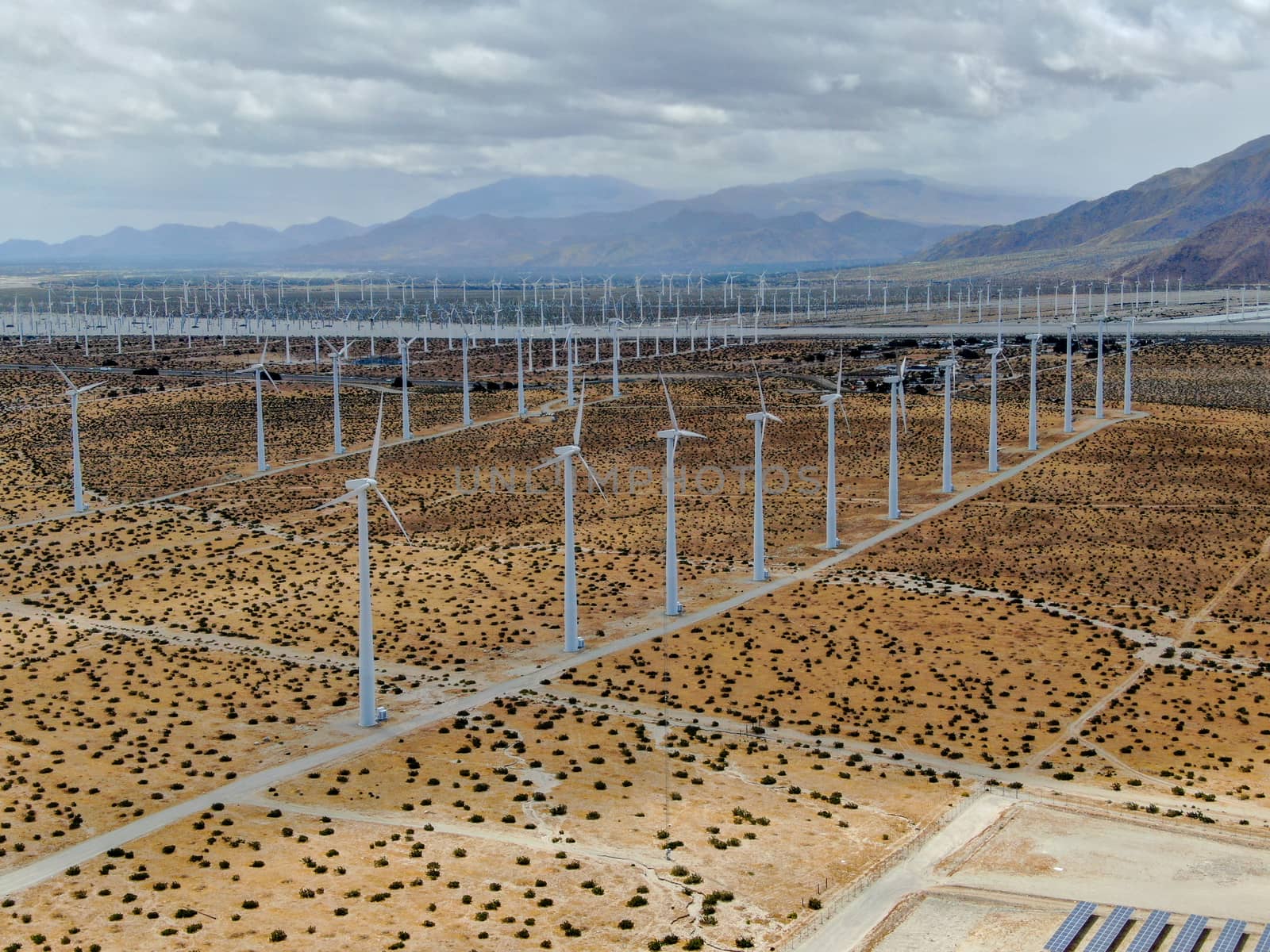 Aerial view of huge array of gigantic wind turbines spreading over the desert in Palm Springs wind farm. California. USA. Aerial view of wind turbines generating electricity. 