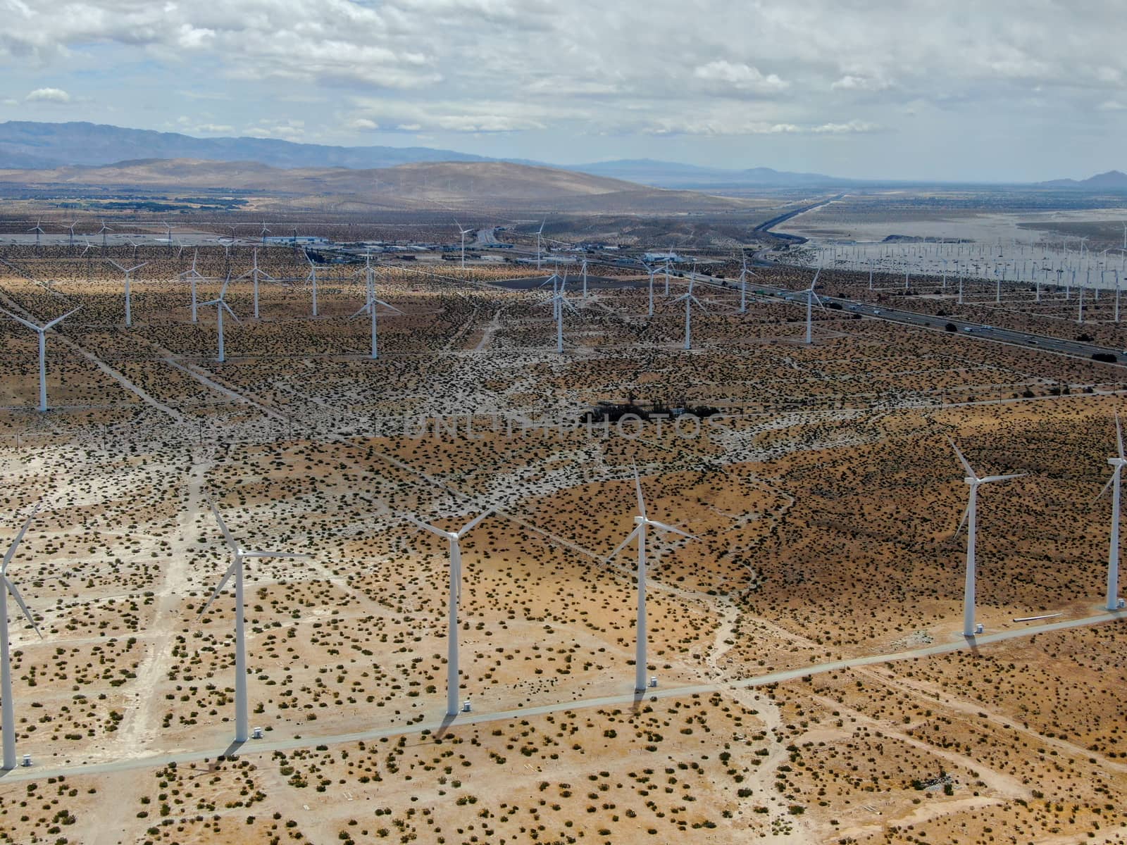 Aerial view of huge array of gigantic wind turbines spreading over the desert in Palm Springs wind farm. California. USA. Aerial view of wind turbines generating electricity. 