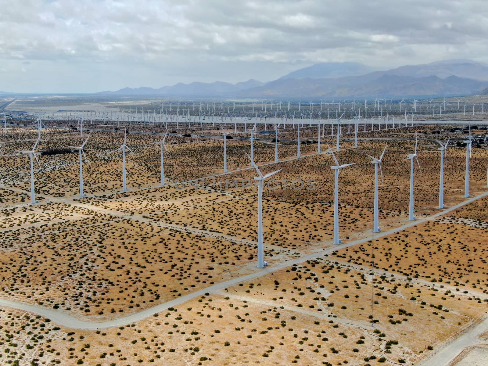 Aerial view of huge array of gigantic wind turbines spreading over the desert in Palm Springs wind farm. California. USA. Aerial view of wind turbines generating electricity. 