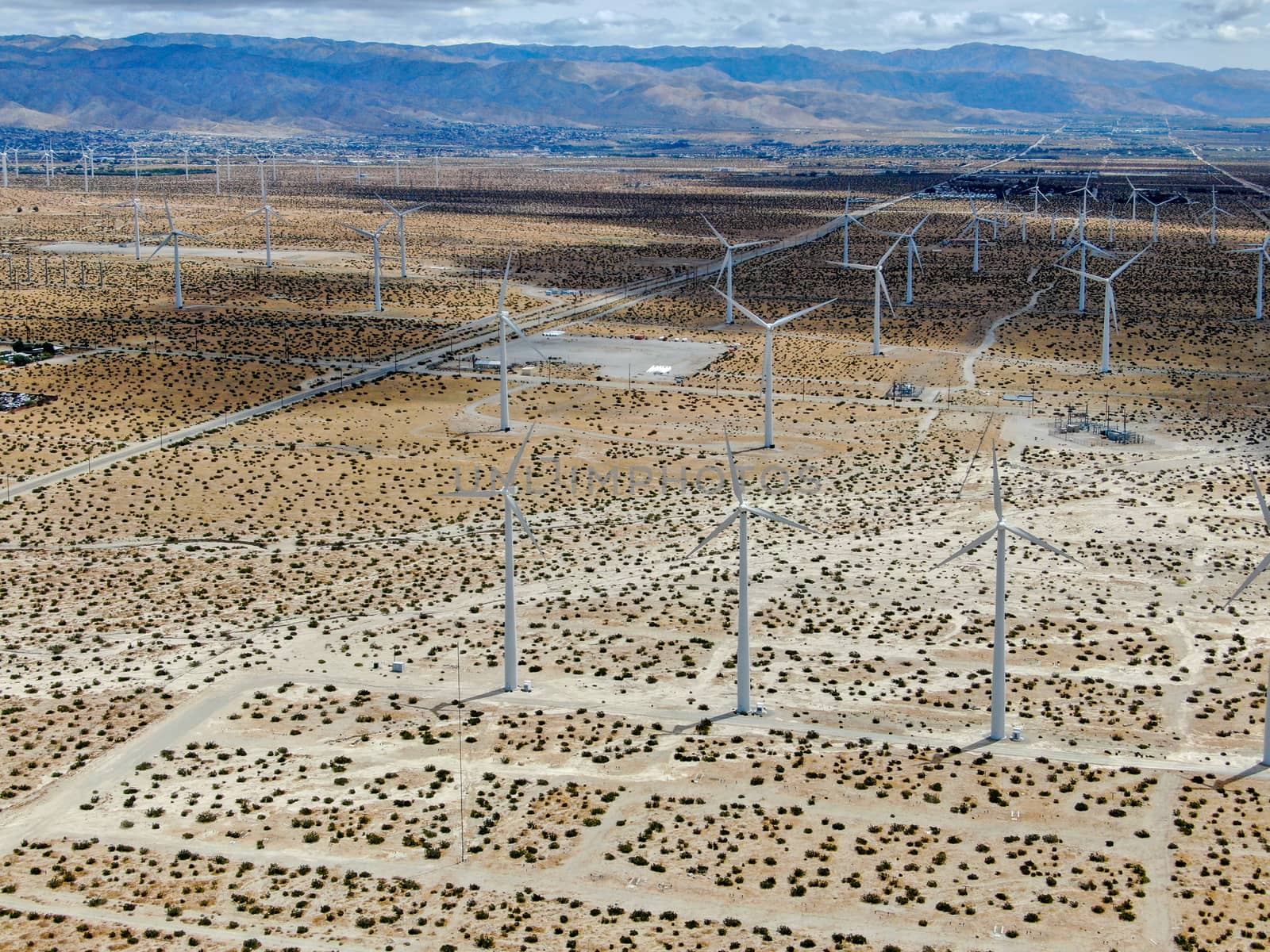 Aerial view of huge array of gigantic wind turbines spreading over the desert in Palm Springs wind farm. California. USA. Aerial view of wind turbines generating electricity. 