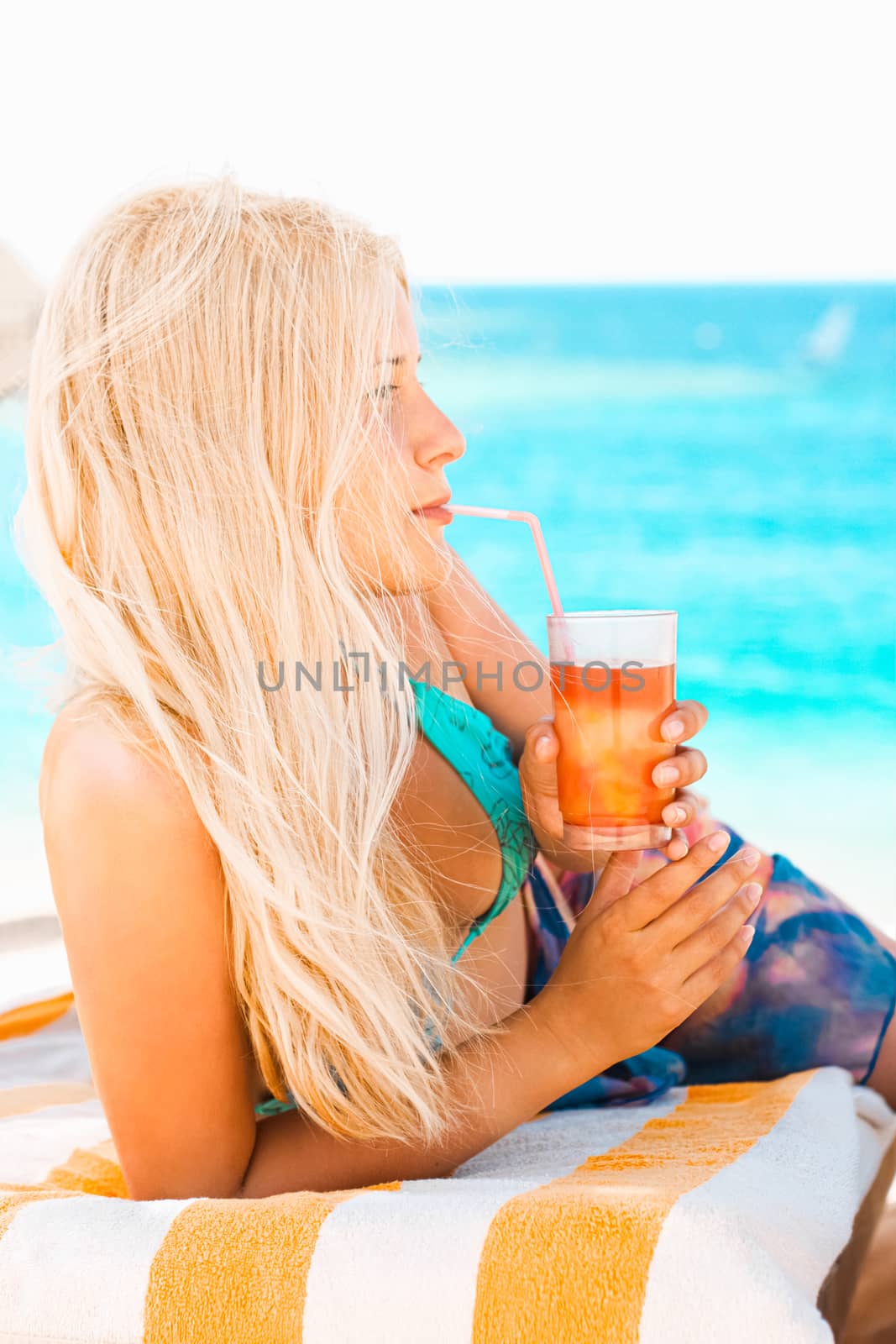 Woman with blond hair enjoying cocktail drink and beach lifestyle in summertime, holiday travel and leisure concept