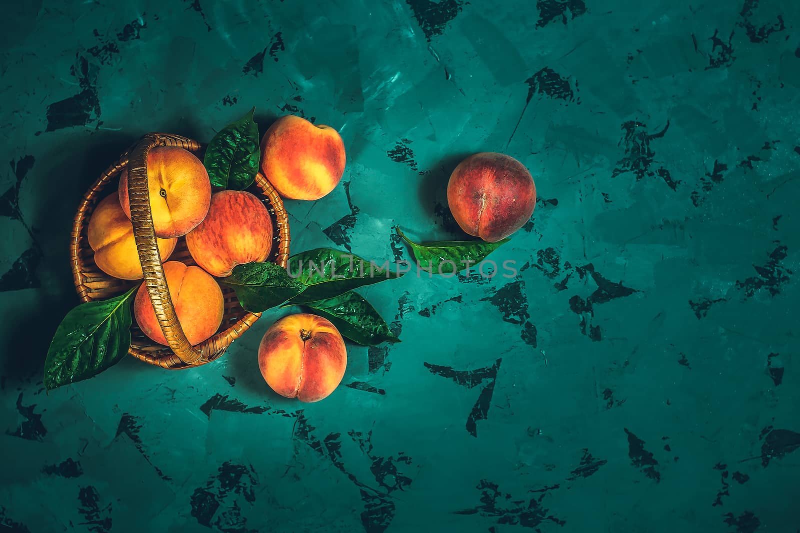 Ripe peaches in basket on a dark background. Top view. Copy space.