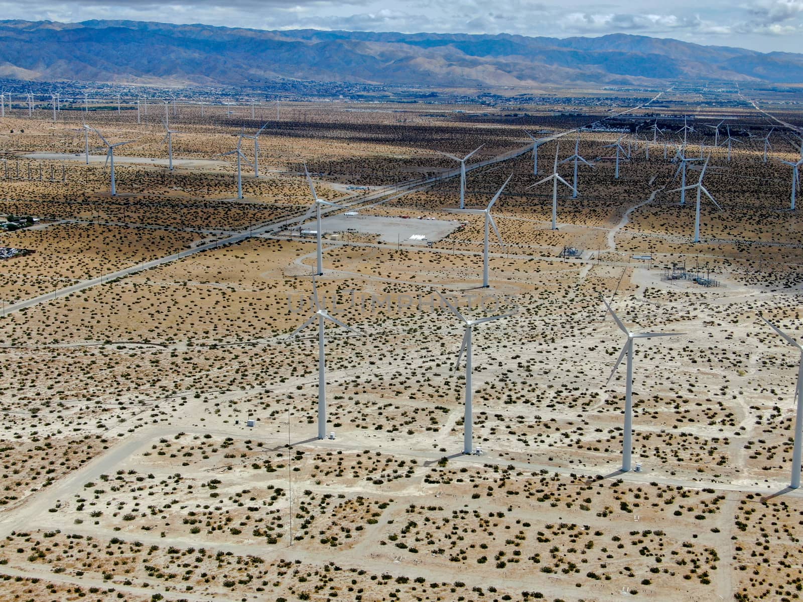 Aerial view of huge array of gigantic wind turbines spreading over the desert in Palm Springs wind farm. California. USA. Aerial view of wind turbines generating electricity. 