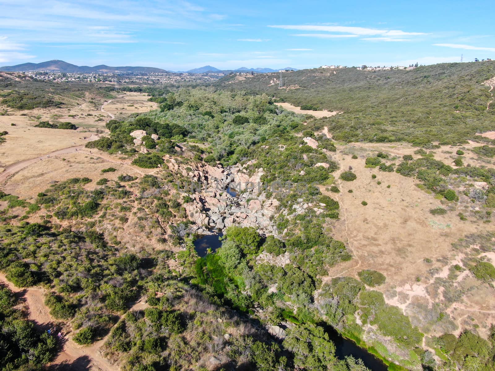 Aerial view of Los Penasquitos Canyon Preserve with the creek waterfall and people enjoying the water. Urban park with trails and river in San Diego, California. USA