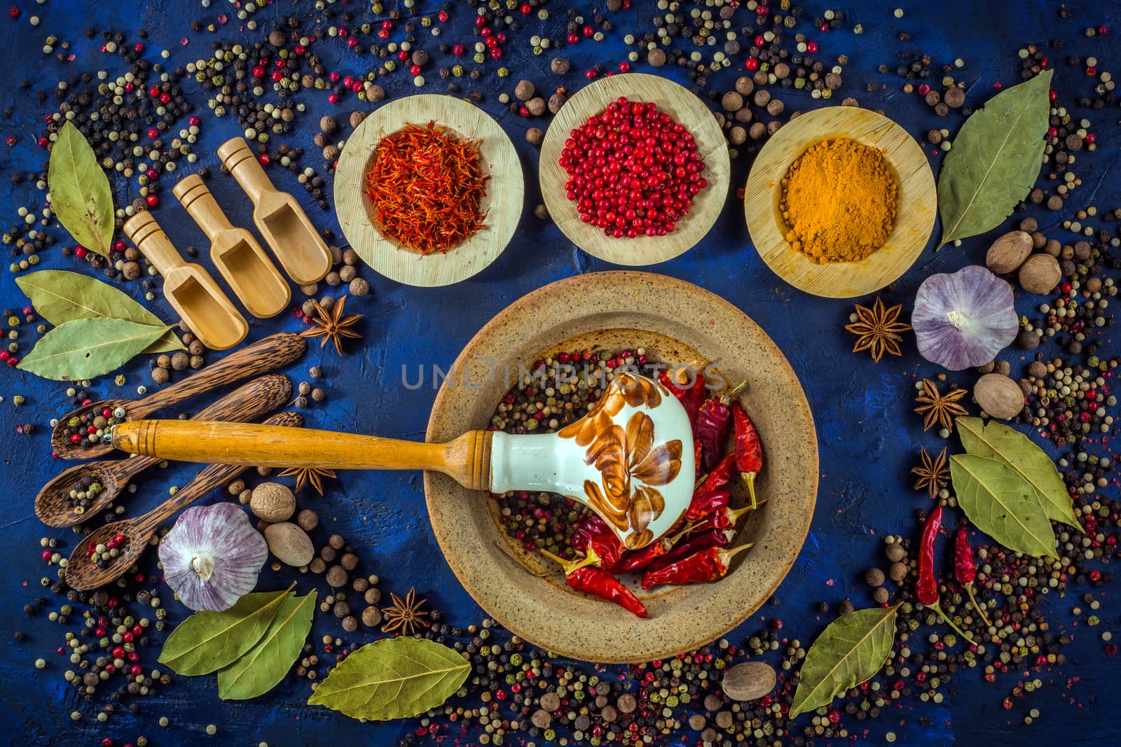 Various fragrant spices on a dark blue background. Vintage pestle and mortar with assortment of pepper mix and hot chili. Various spices inspiring our recipes while we cook at home.  Top view. Flat-lay.