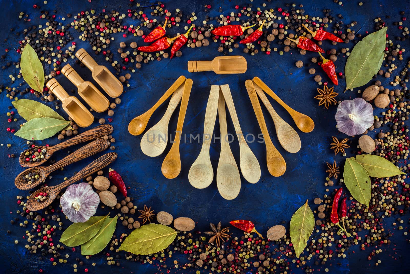 Various spices and wooden spoons on a dark blue background. Spicy background concept with various wooden spoons. Cooking at home. Top view, close up, flat-lay.