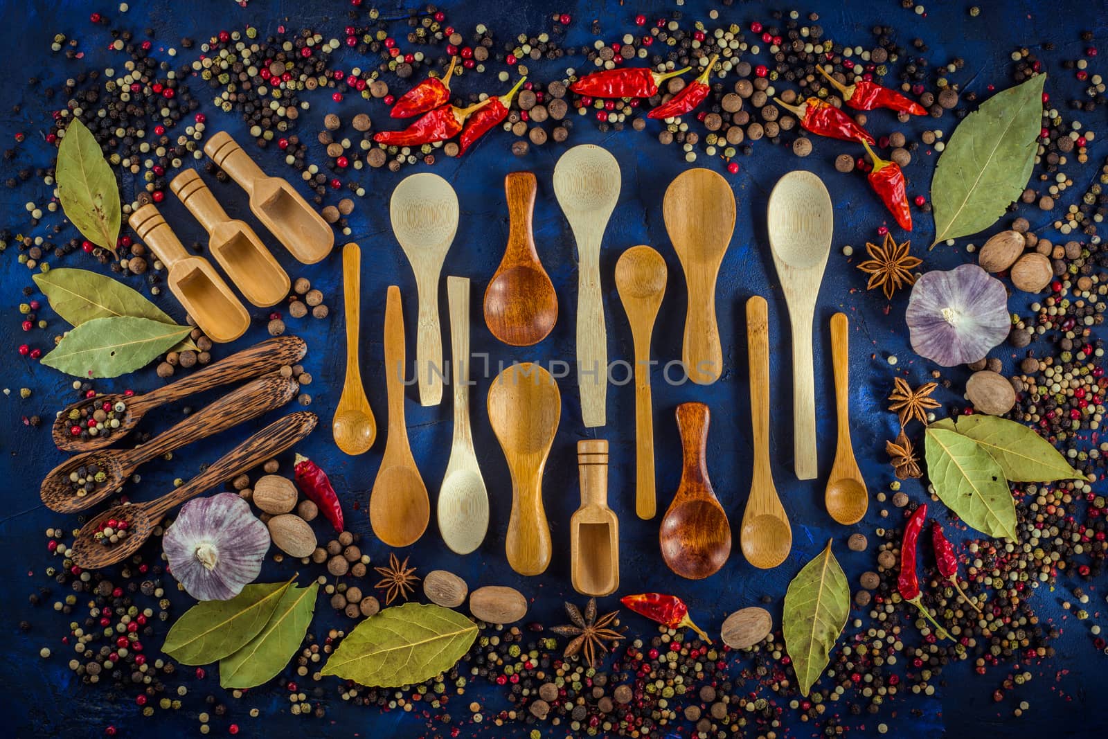 Various spices and wooden spoons on a dark blue background. Spicy background concept with various wooden spoons.  Cooking at home. Top view, close up, flat-lay.