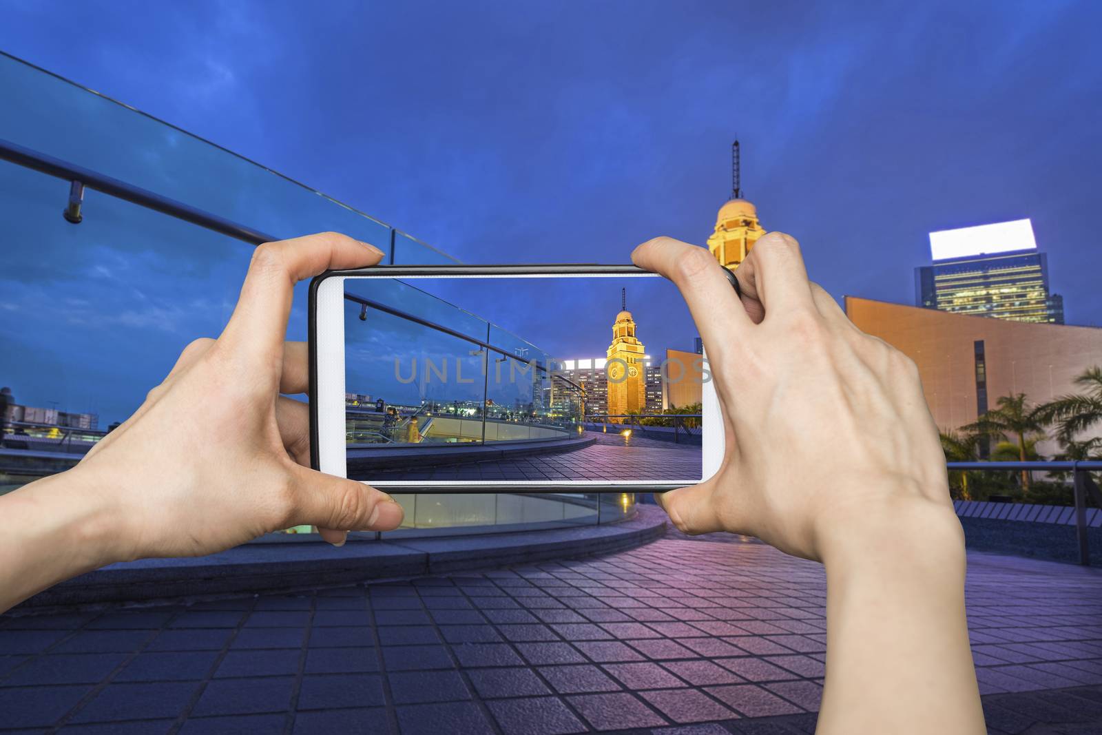 Girl taking pictures on mobile smart phone in Night view Old Clock Tower in Hong Kong