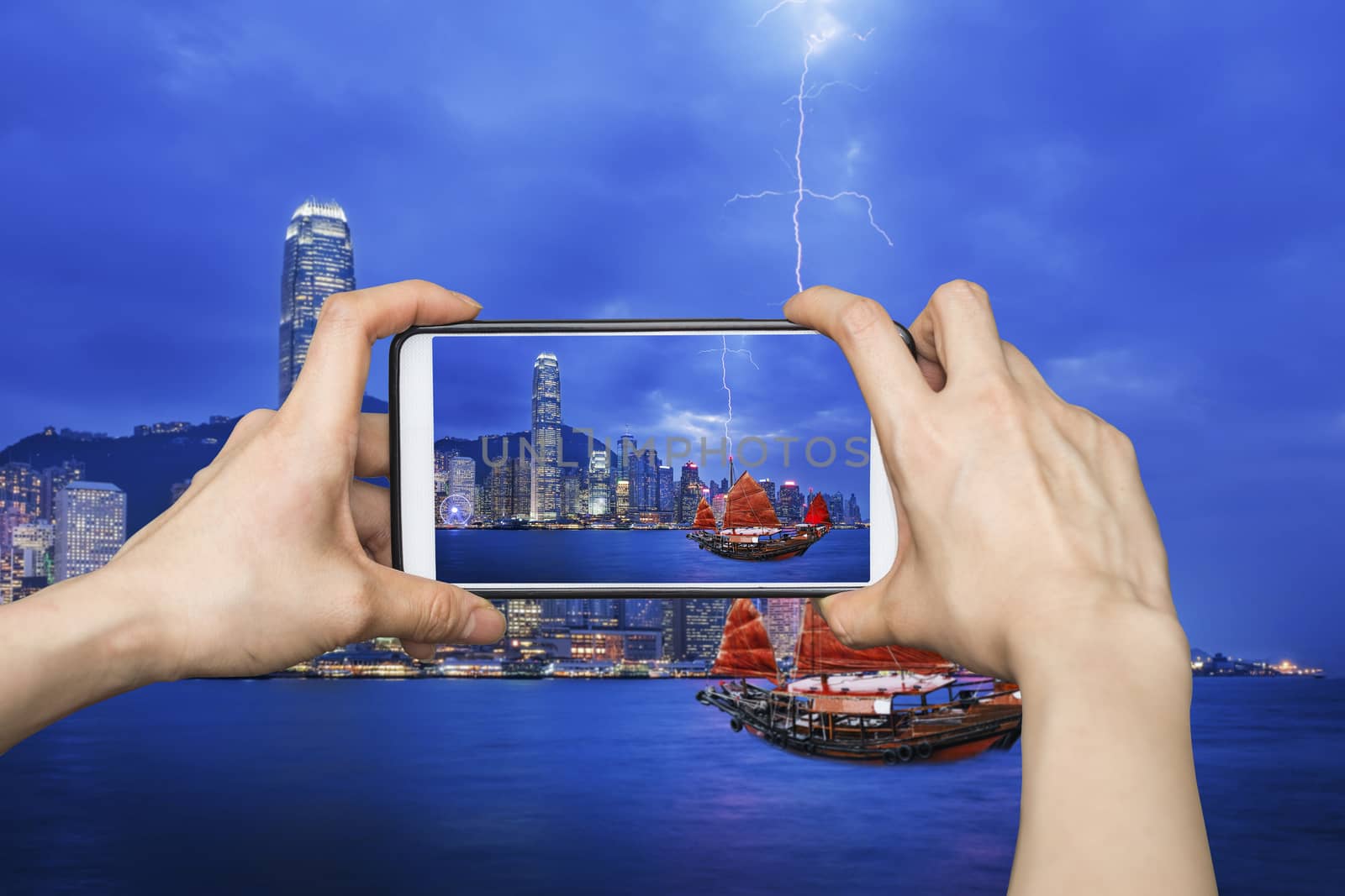 Girl taking pictures on mobile smart phone in HongKong cityscape at night , Hong kong city.